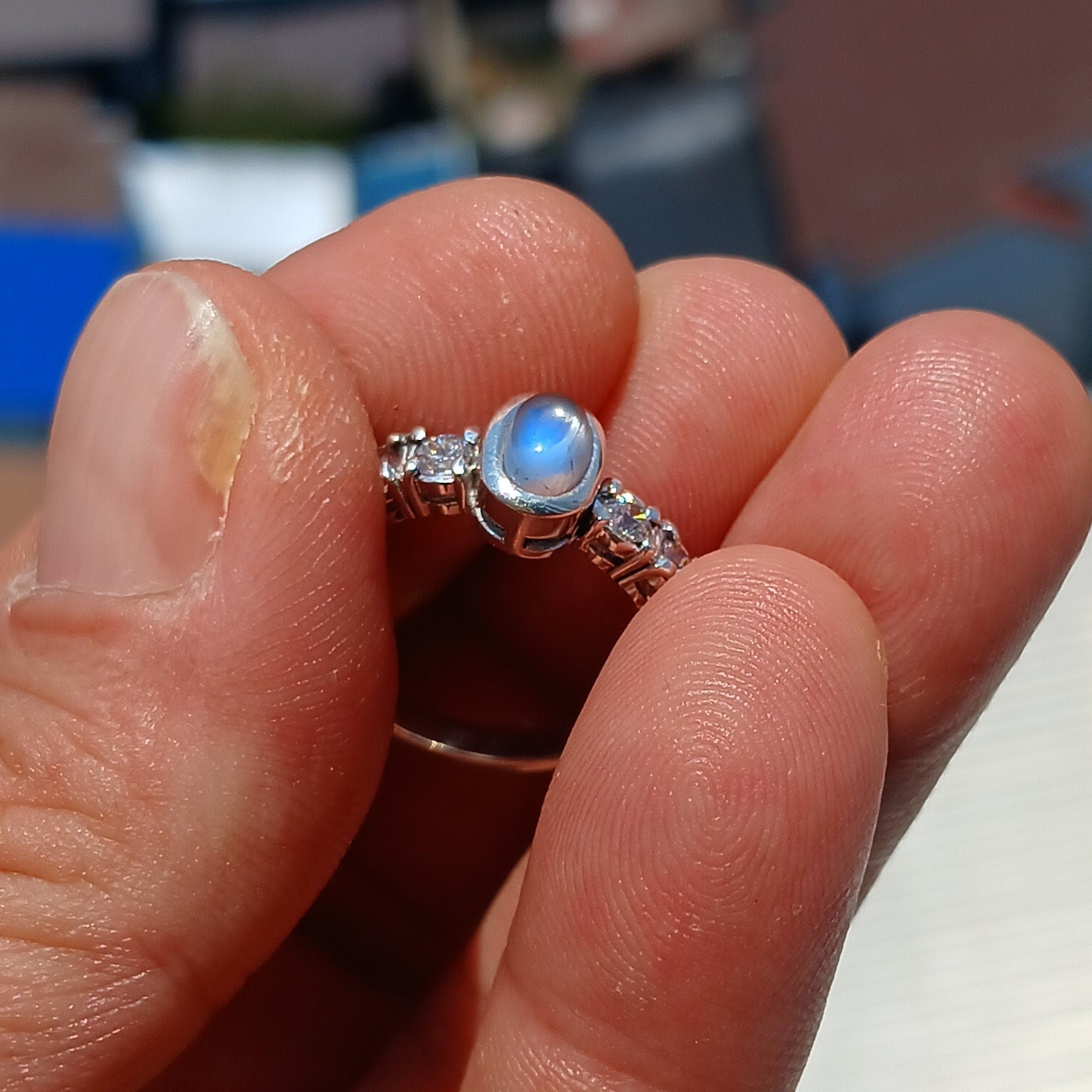 A beautiful Moonstone Ring featuring an oval Ceylon Moonstone surrounded by four sparkling CZ stones, crafted in high-quality sterling silver.