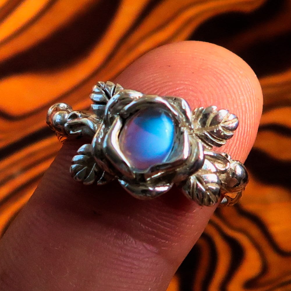 A beautiful Moonstone Silver Ring featuring an oval Moonstone set in polished Sterling Silver with a delicate rose flower design.