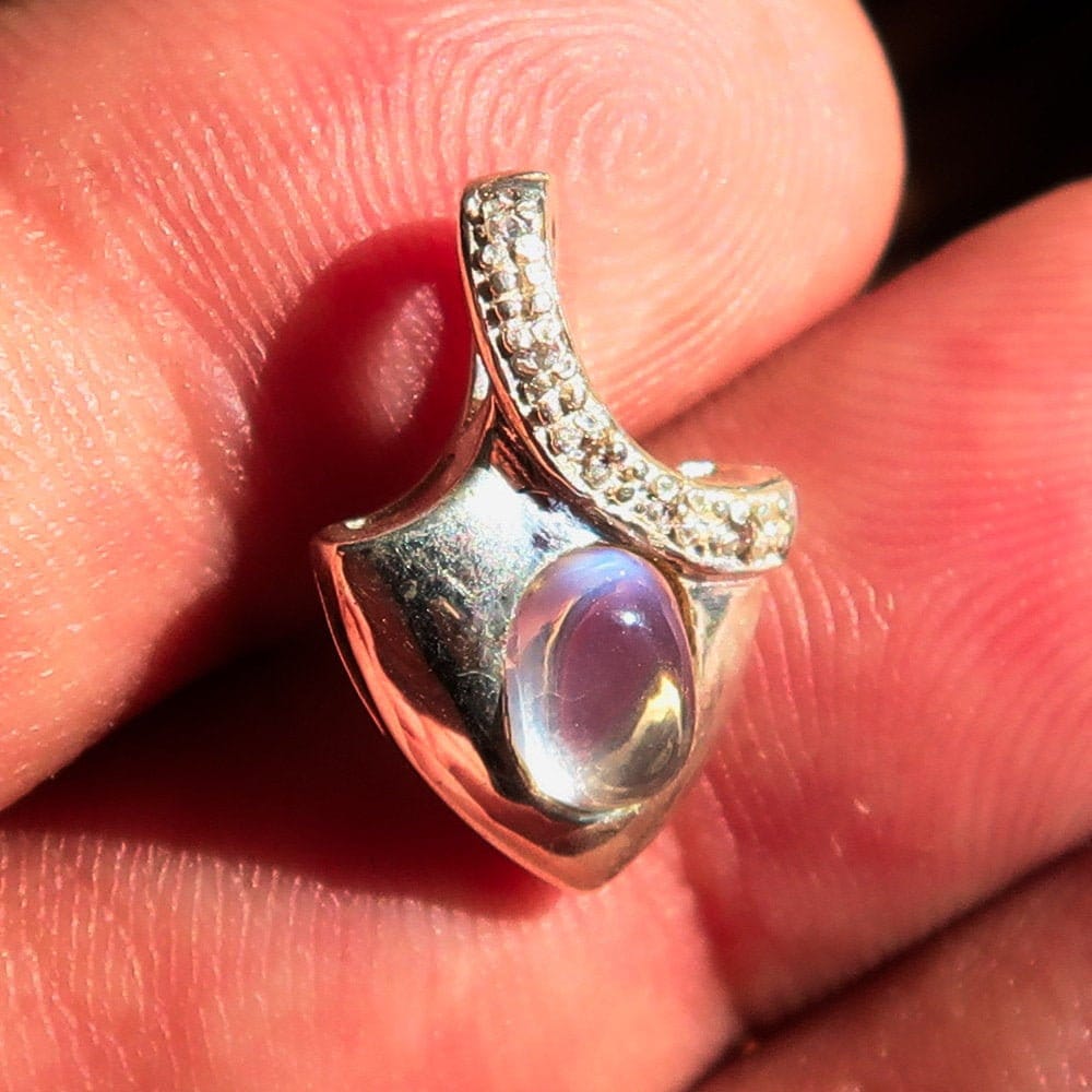 A stunning Moonstone Silver Pendant featuring an oval Ceylon Moonstone surrounded by sparkling Cubic Zirconias, crafted from high-quality sterling silver.