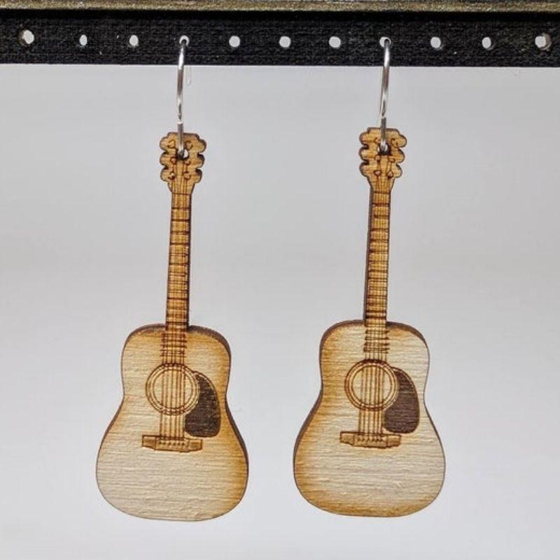 A pair of Musical Instruments Natural Wood Earrings featuring miniature wooden instruments like guitars and drums, crafted from lightweight Birchwood.