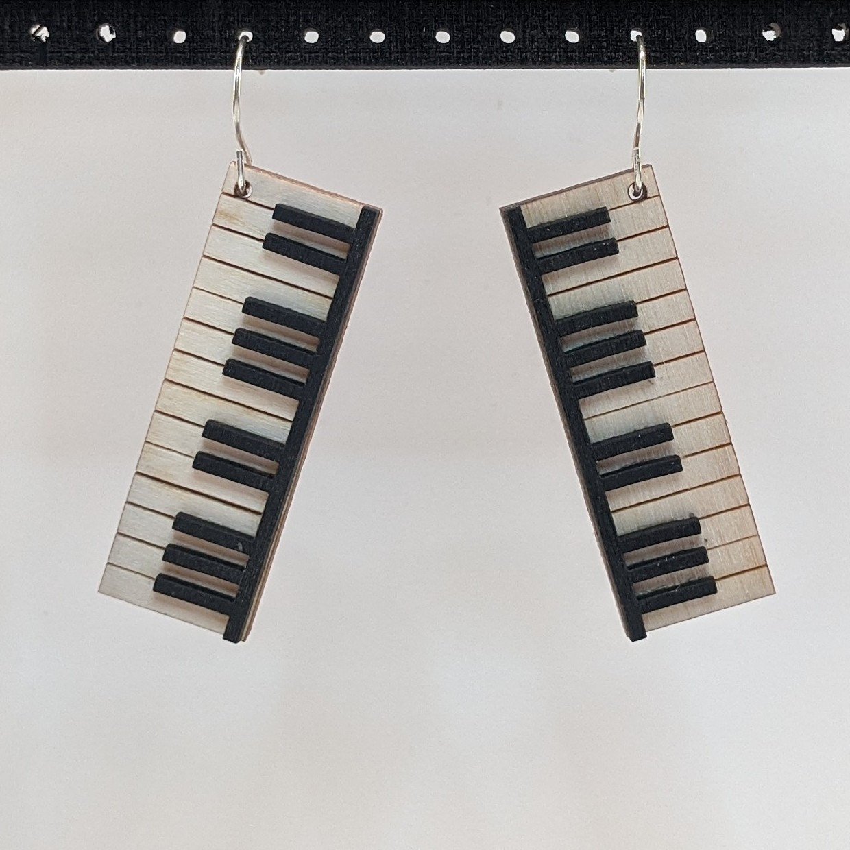 A pair of Musical Instruments Natural Wood Earrings featuring miniature wooden instruments like guitars and drums, crafted from lightweight Birchwood.