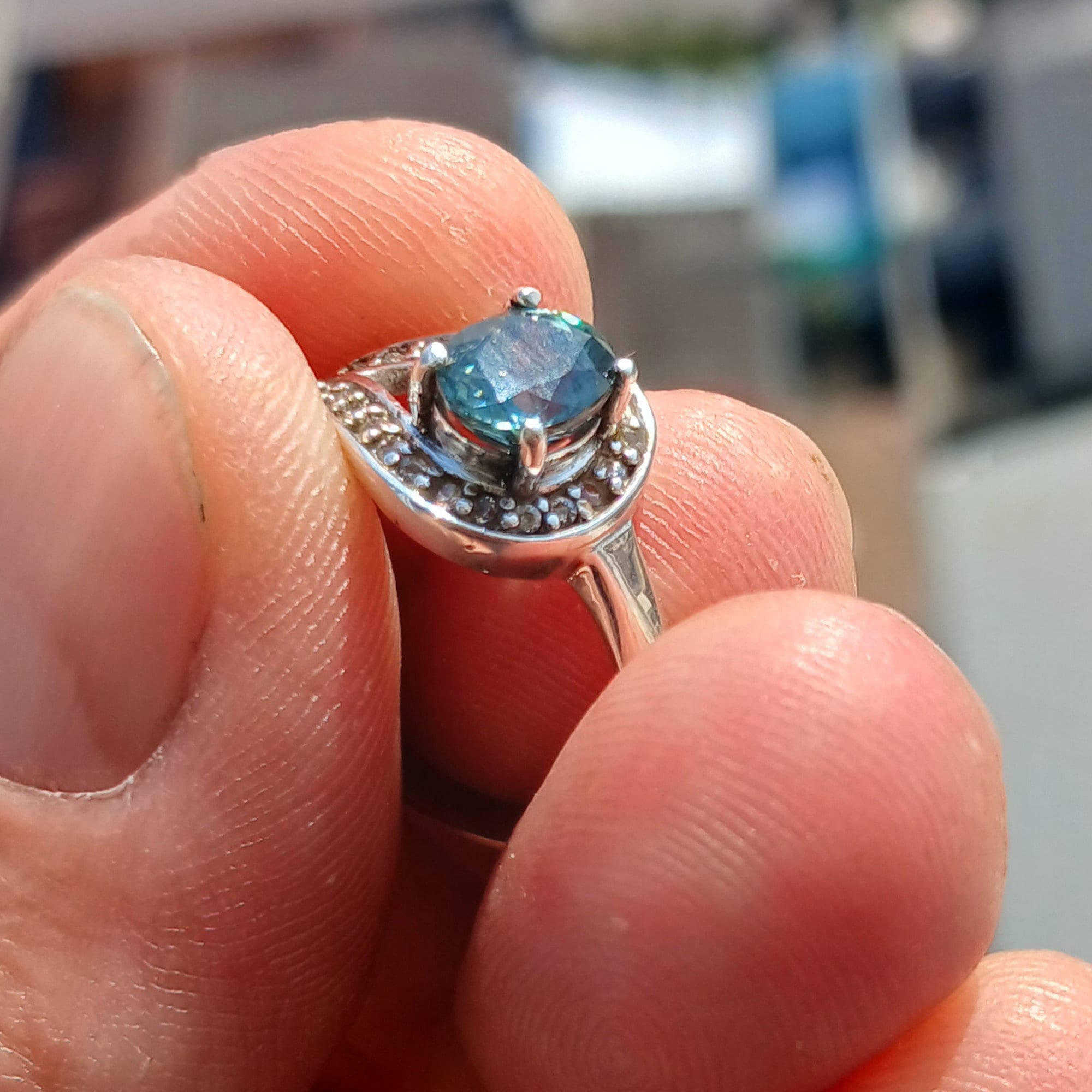 Natural Blue Zircon Ring featuring an oval cut blue gemstone surrounded by 21 sparkling CZ stones on a polished sterling silver band.