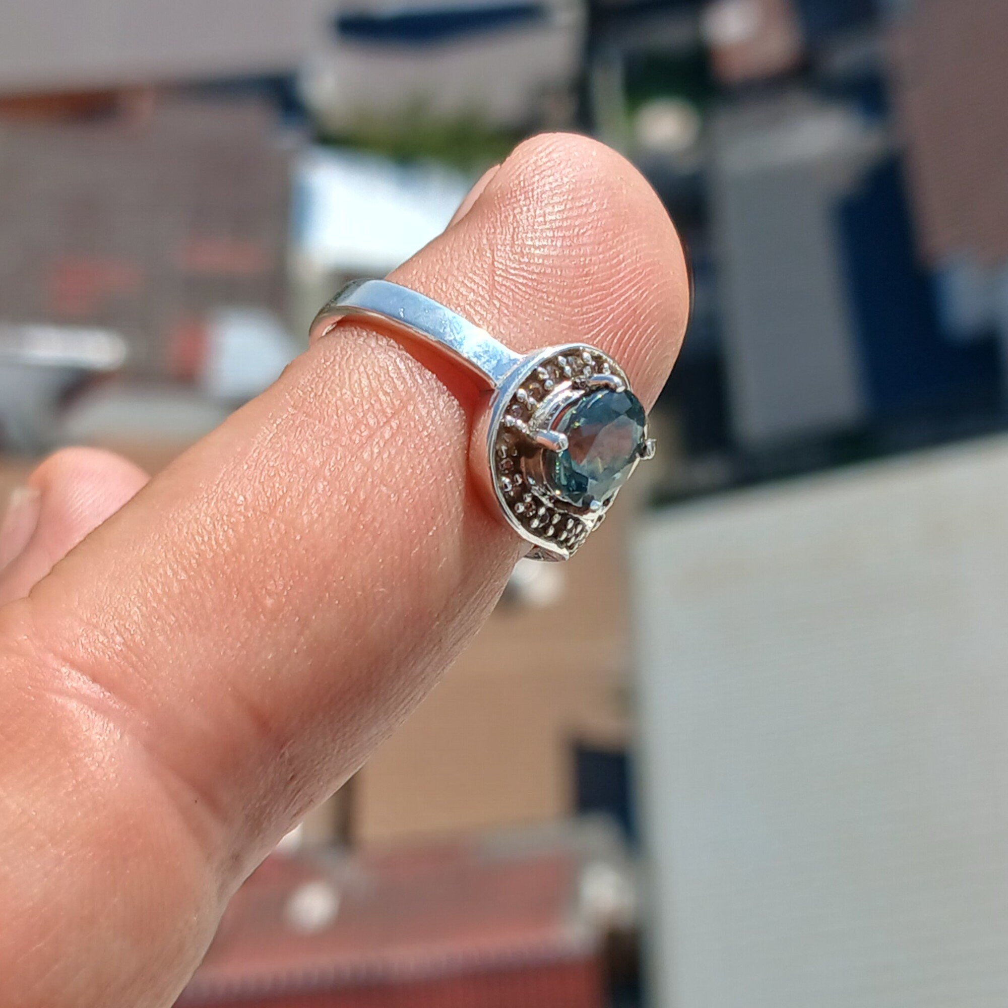 Natural Blue Zircon Ring featuring an oval cut blue gemstone surrounded by 21 sparkling CZ stones on a polished sterling silver band.