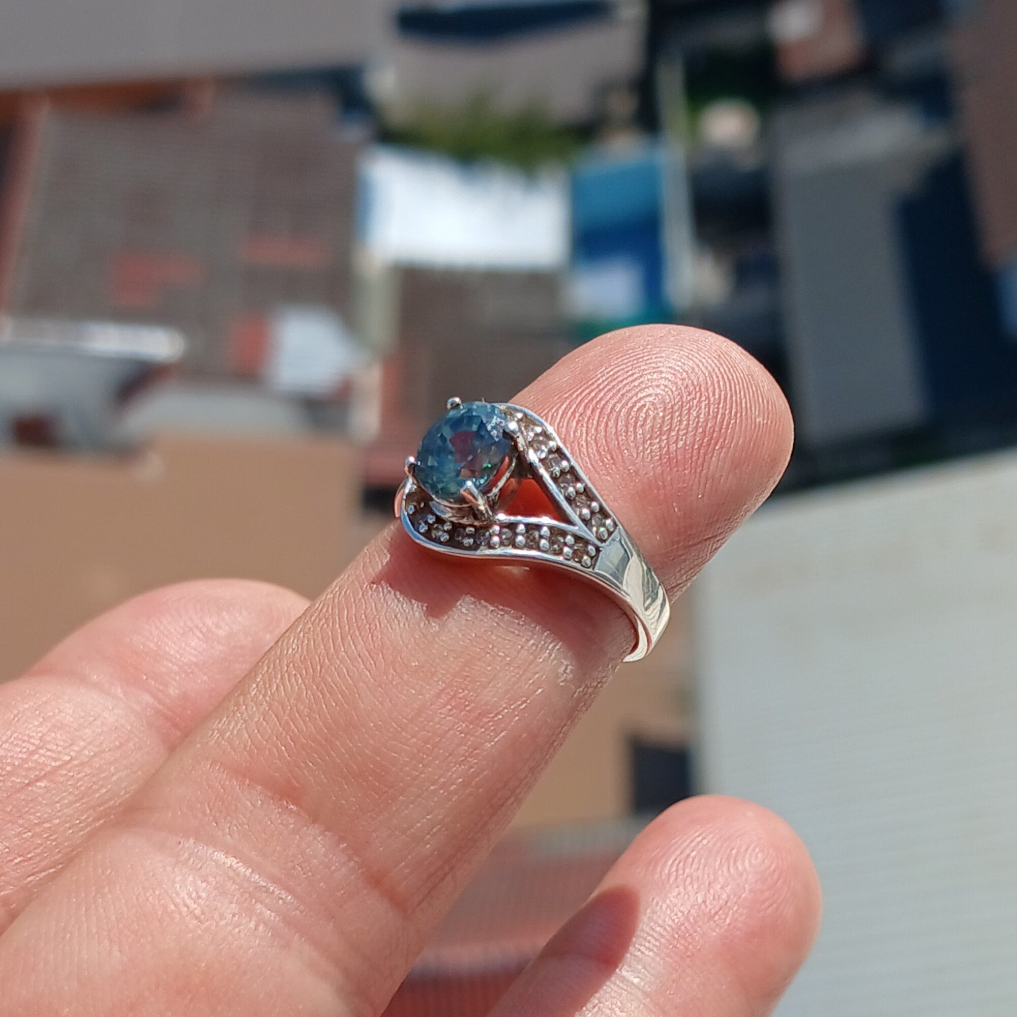 Natural Blue Zircon Ring featuring an oval cut blue gemstone surrounded by 21 sparkling CZ stones on a polished sterling silver band.