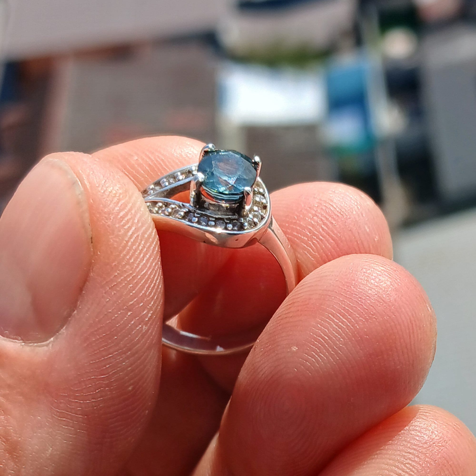 Natural Blue Zircon Ring featuring an oval cut blue gemstone surrounded by 21 sparkling CZ stones on a polished sterling silver band.