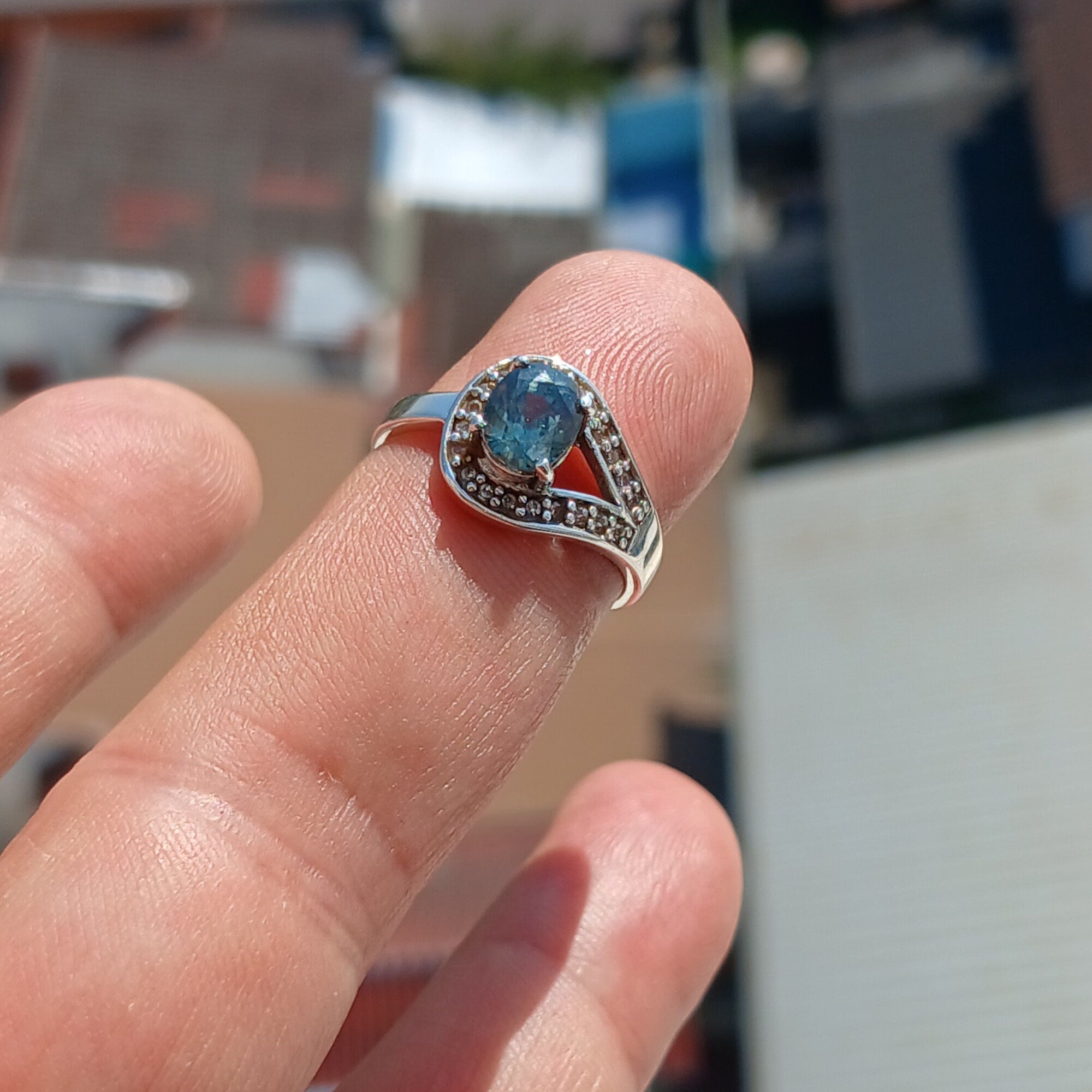 Natural Blue Zircon Ring featuring an oval cut blue gemstone surrounded by 21 sparkling CZ stones on a polished sterling silver band.