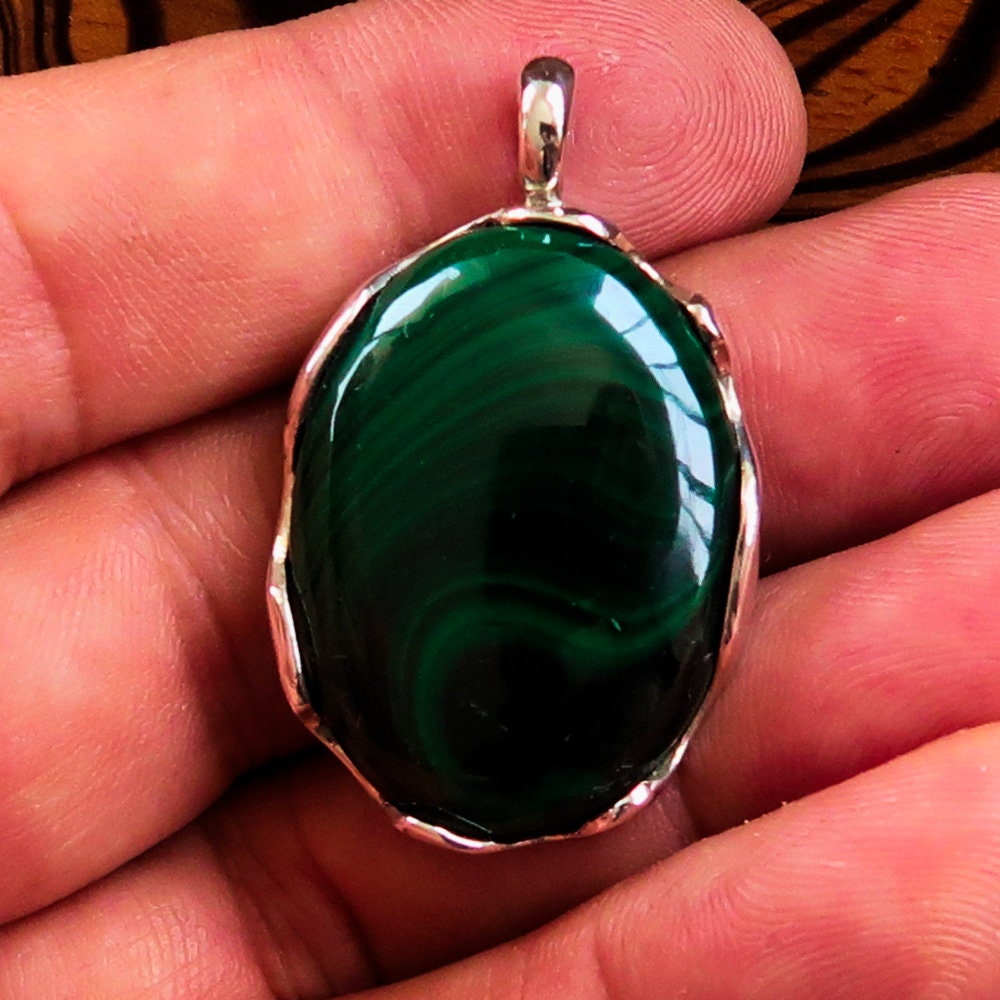 Natural Malachite Amulet set in a Sterling Silver Pendant, featuring an oval-shaped green Malachite cabochon with intricate patterns.