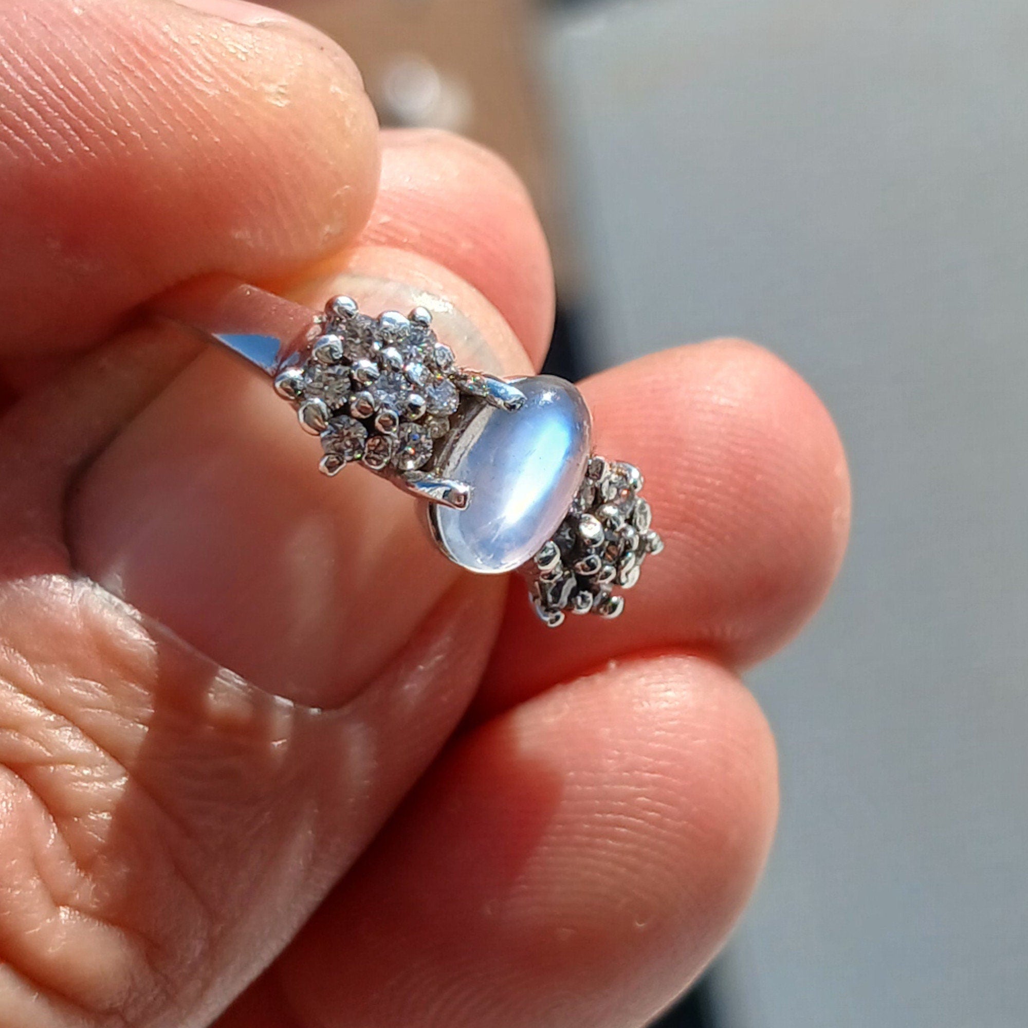 A beautiful handmade Natural Moonstone Ring featuring an oval Ceylon Moonstone surrounded by 14 sparkling CZ stones in a polished sterling silver band.
