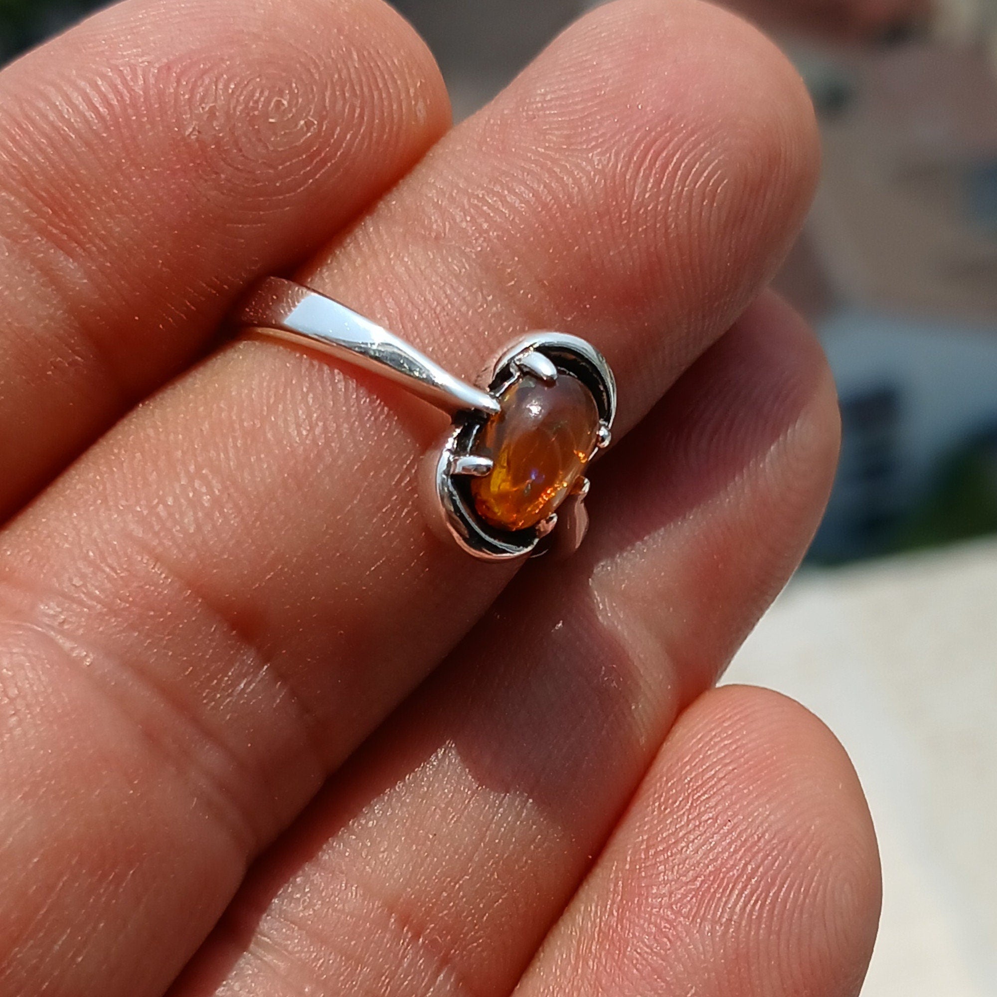 A beautiful Natural Opal Ring featuring an oval-shaped opal set in a polished sterling silver band, showcasing vibrant colors and elegant design.