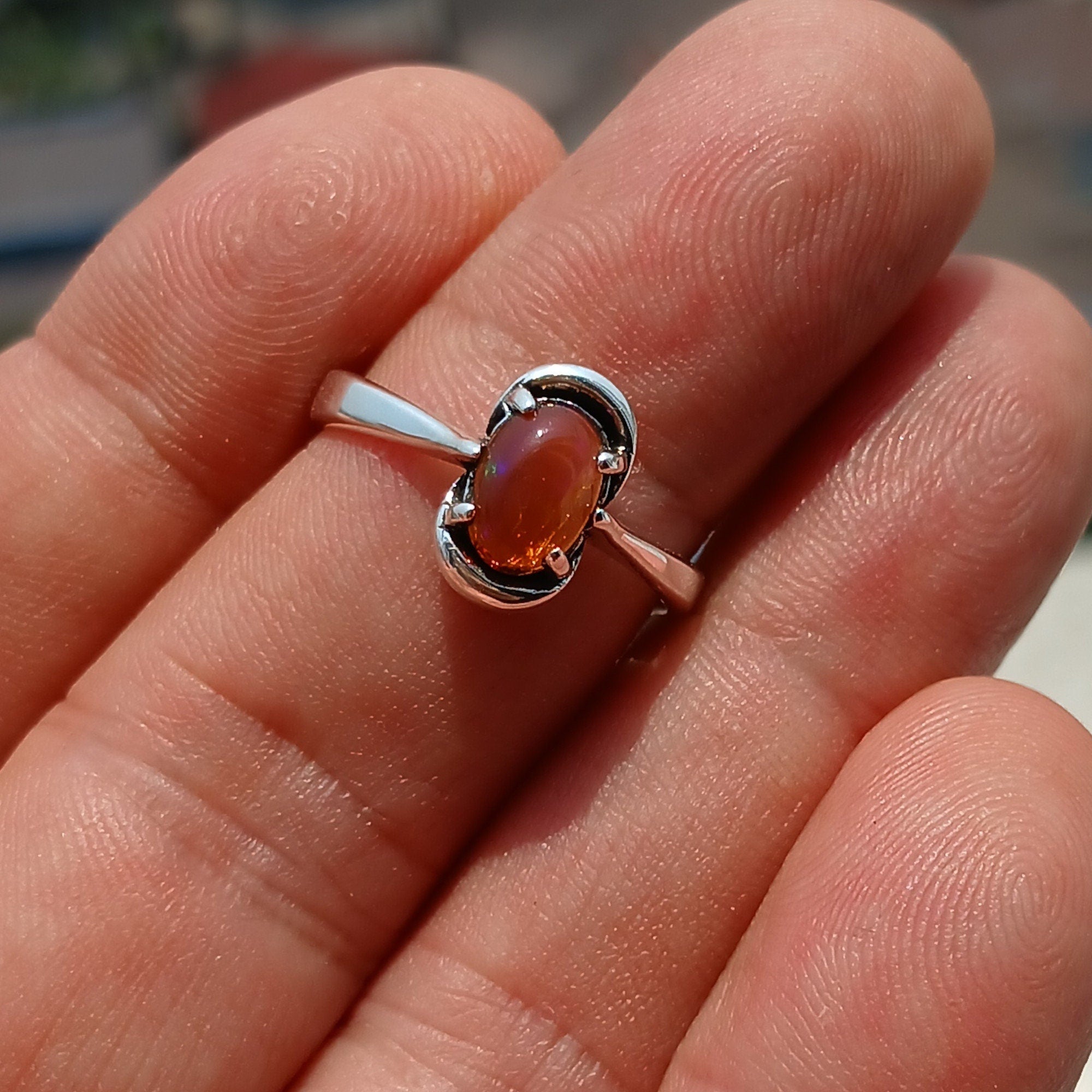 A beautiful Natural Opal Ring featuring an oval-shaped opal set in a polished sterling silver band, showcasing vibrant colors and elegant design.