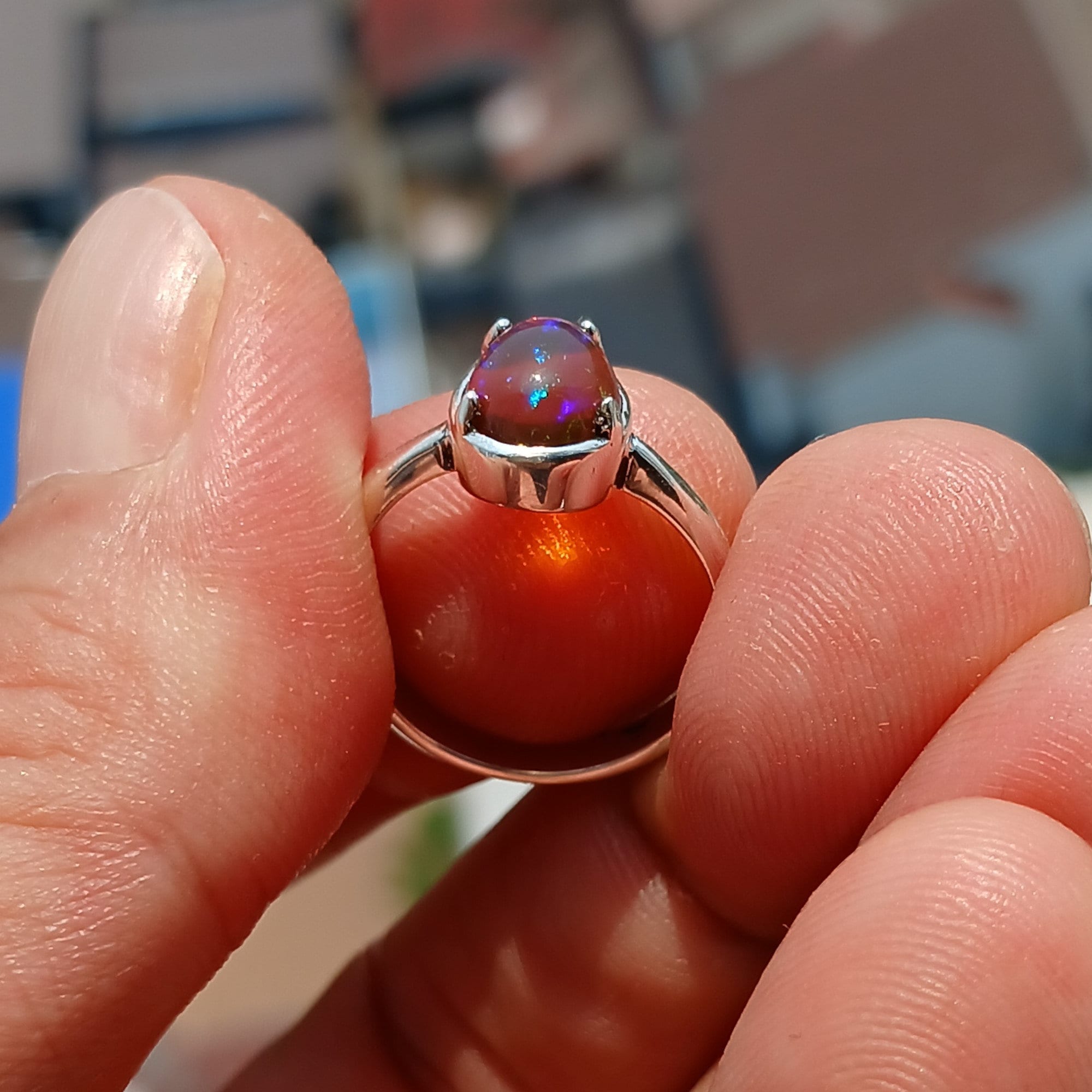 A handcrafted sterling silver solitaire ring featuring a vibrant oval opal, showcasing its unique colors and patterns against a polished silver band.
