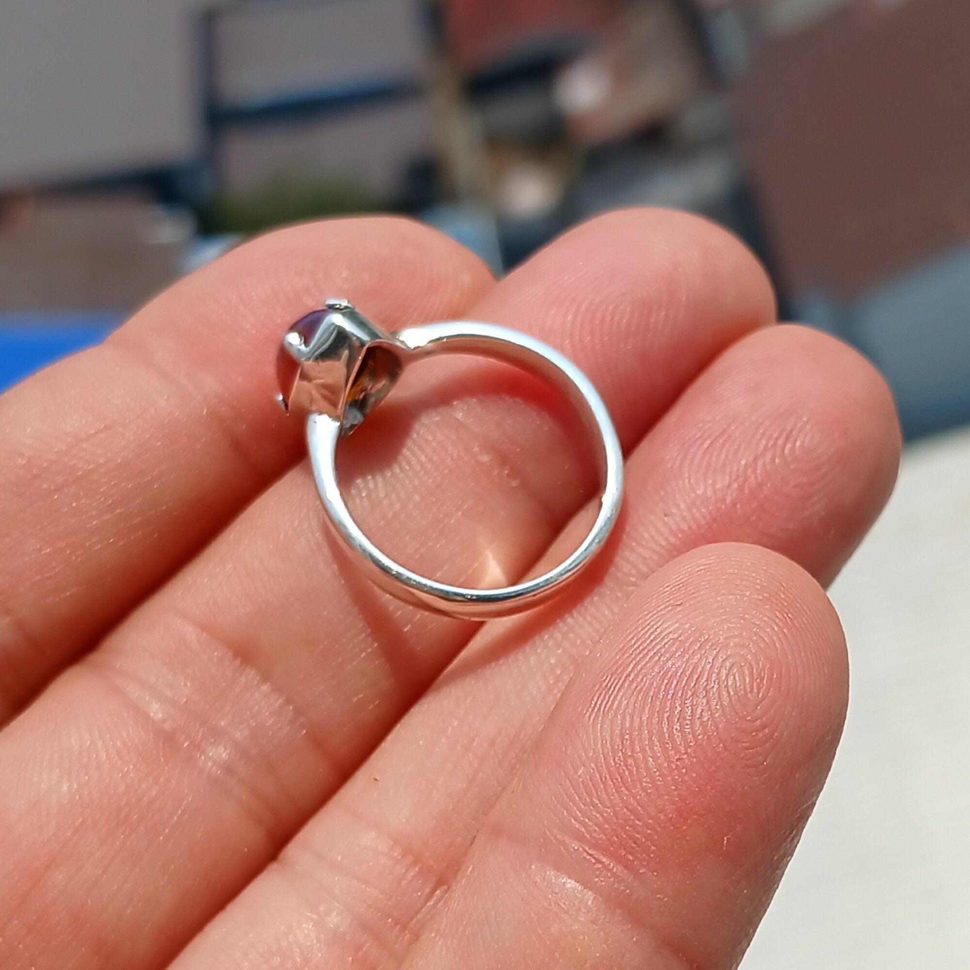 A handcrafted sterling silver solitaire ring featuring a vibrant oval opal, showcasing its unique colors and patterns against a polished silver band.