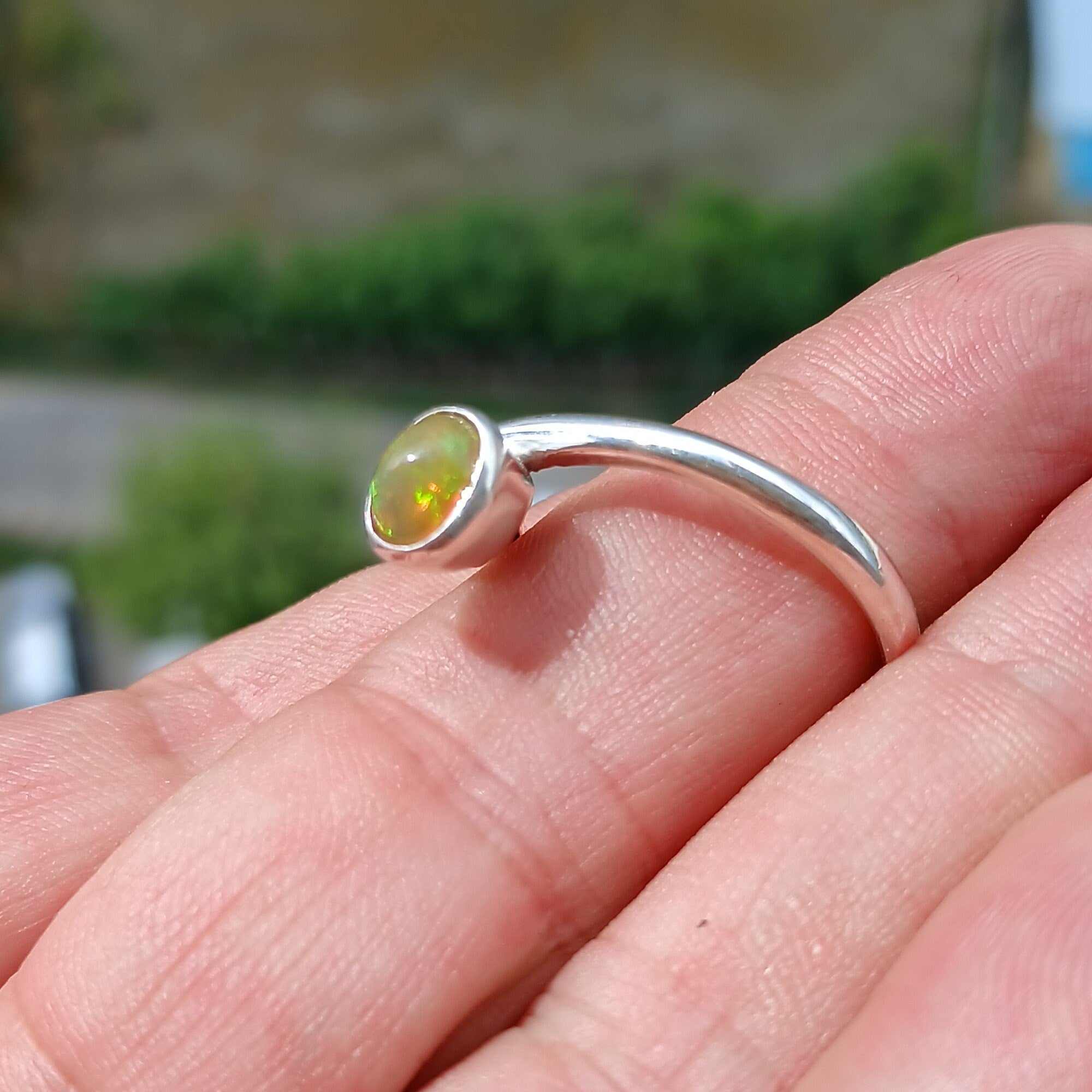 A beautifully handcrafted sterling silver Opal Ring featuring an oval-shaped opal with vibrant colors, set in a minimalist design.