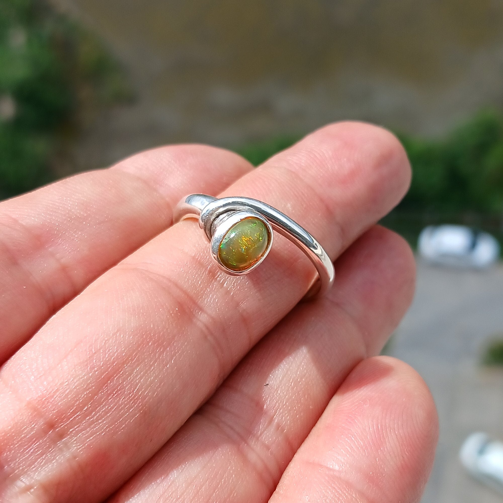 A beautifully handcrafted sterling silver Opal Ring featuring an oval-shaped opal with vibrant colors, set in a minimalist design.