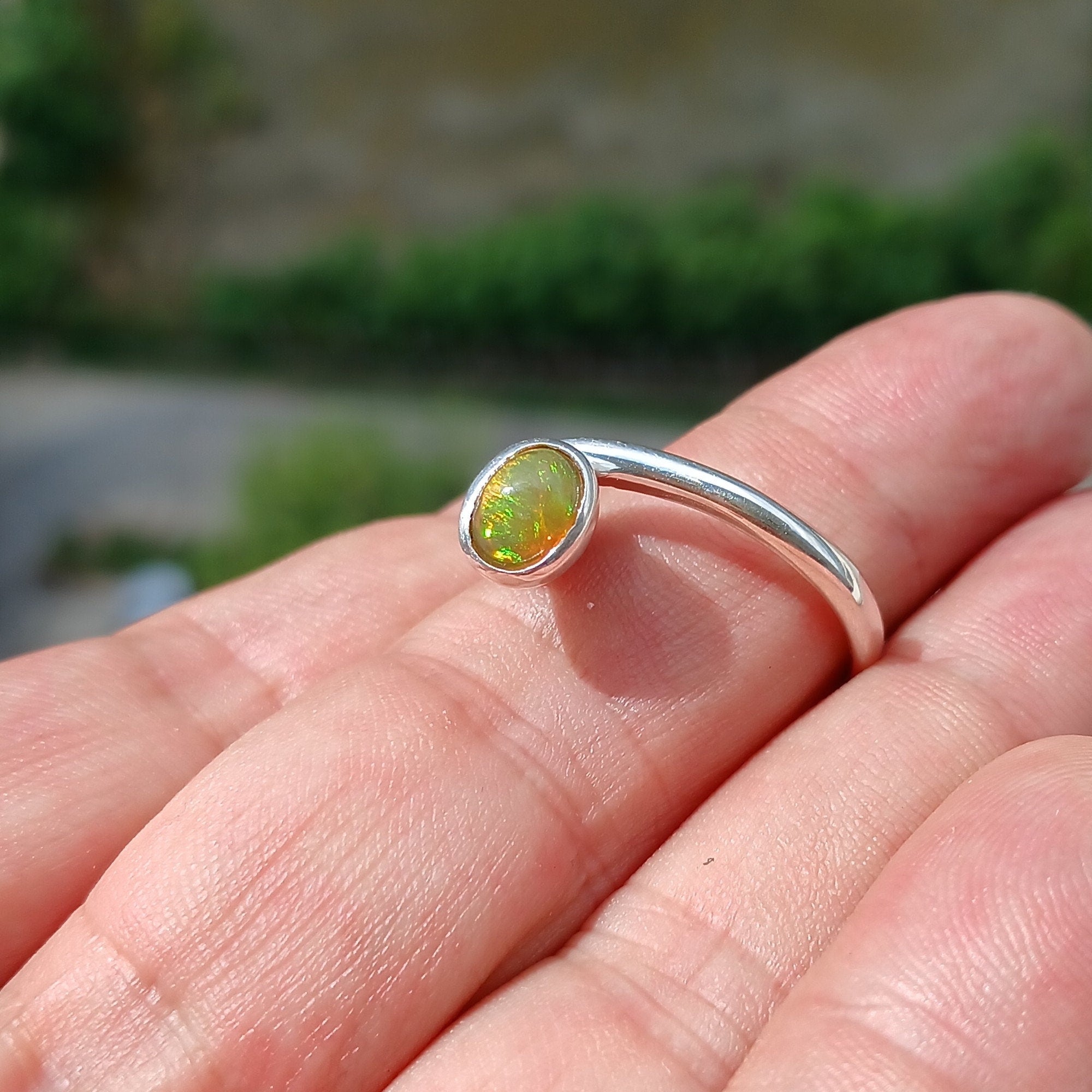 A beautifully handcrafted sterling silver Opal Ring featuring an oval-shaped opal with vibrant colors, set in a minimalist design.