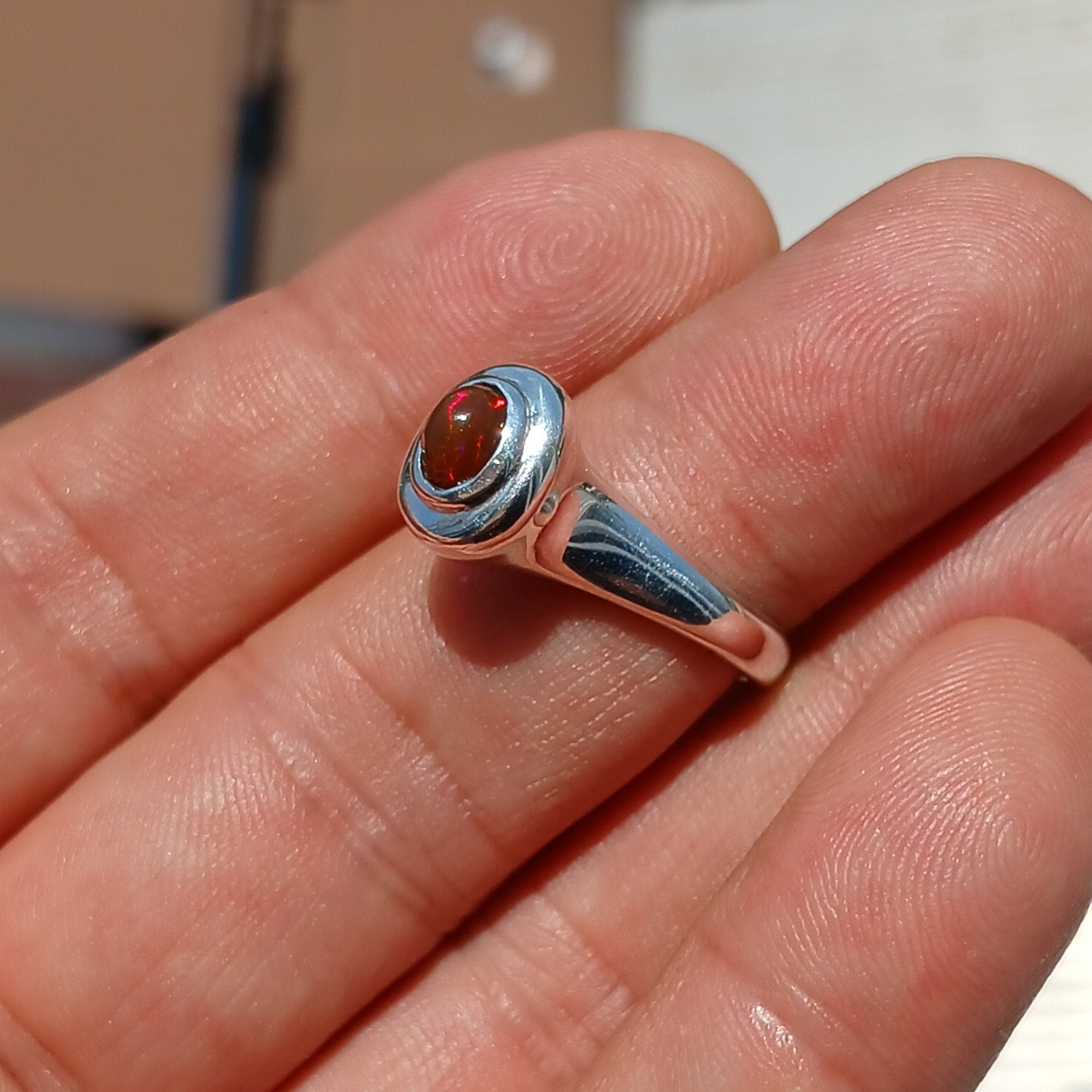 A beautifully handcrafted sterling silver Opal Ring featuring an oval-shaped opal with vibrant red colors, elegantly polished for a sophisticated look.