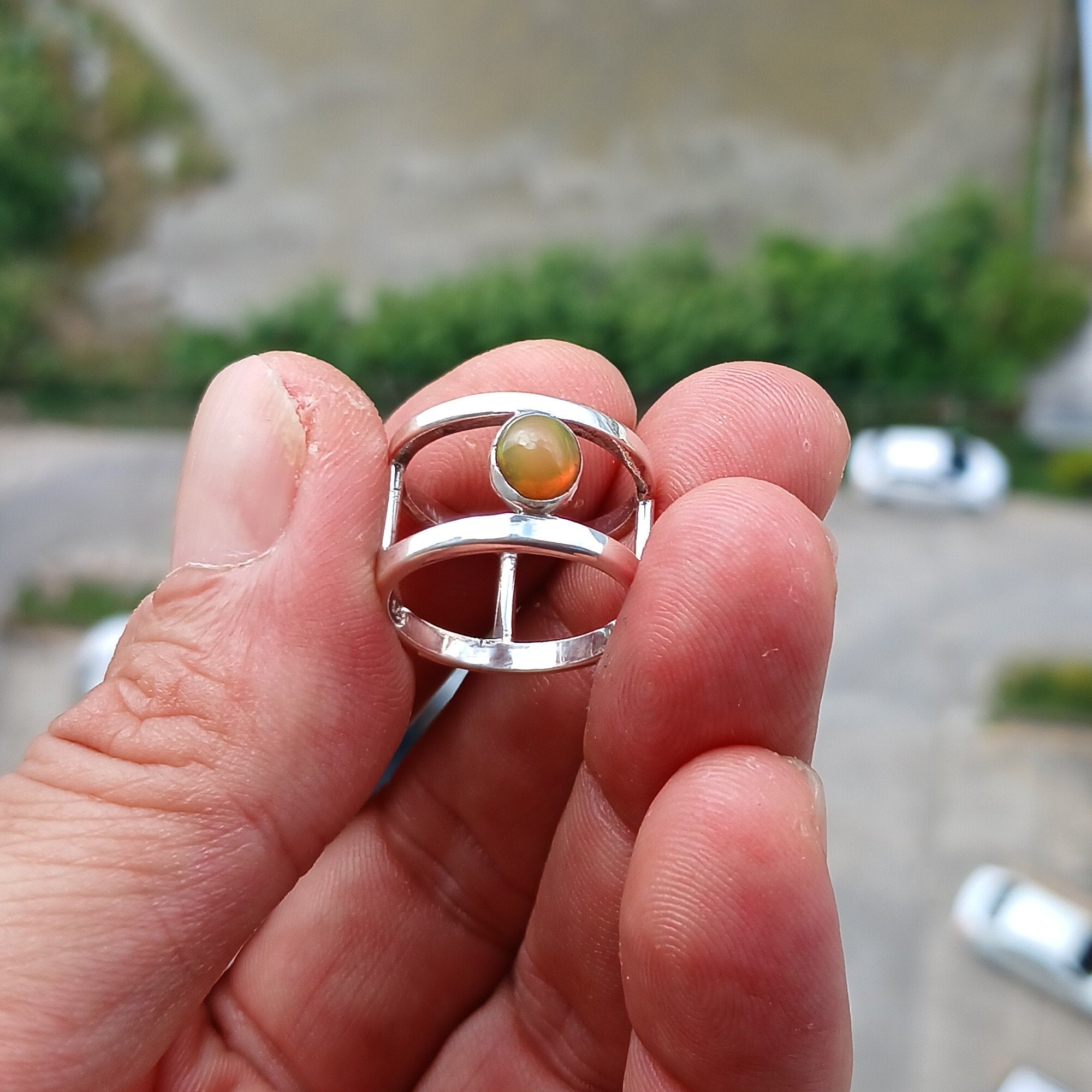 A handcrafted sterling silver solitaire ring featuring a vibrant oval opal, showcasing its unique colors and patterns.