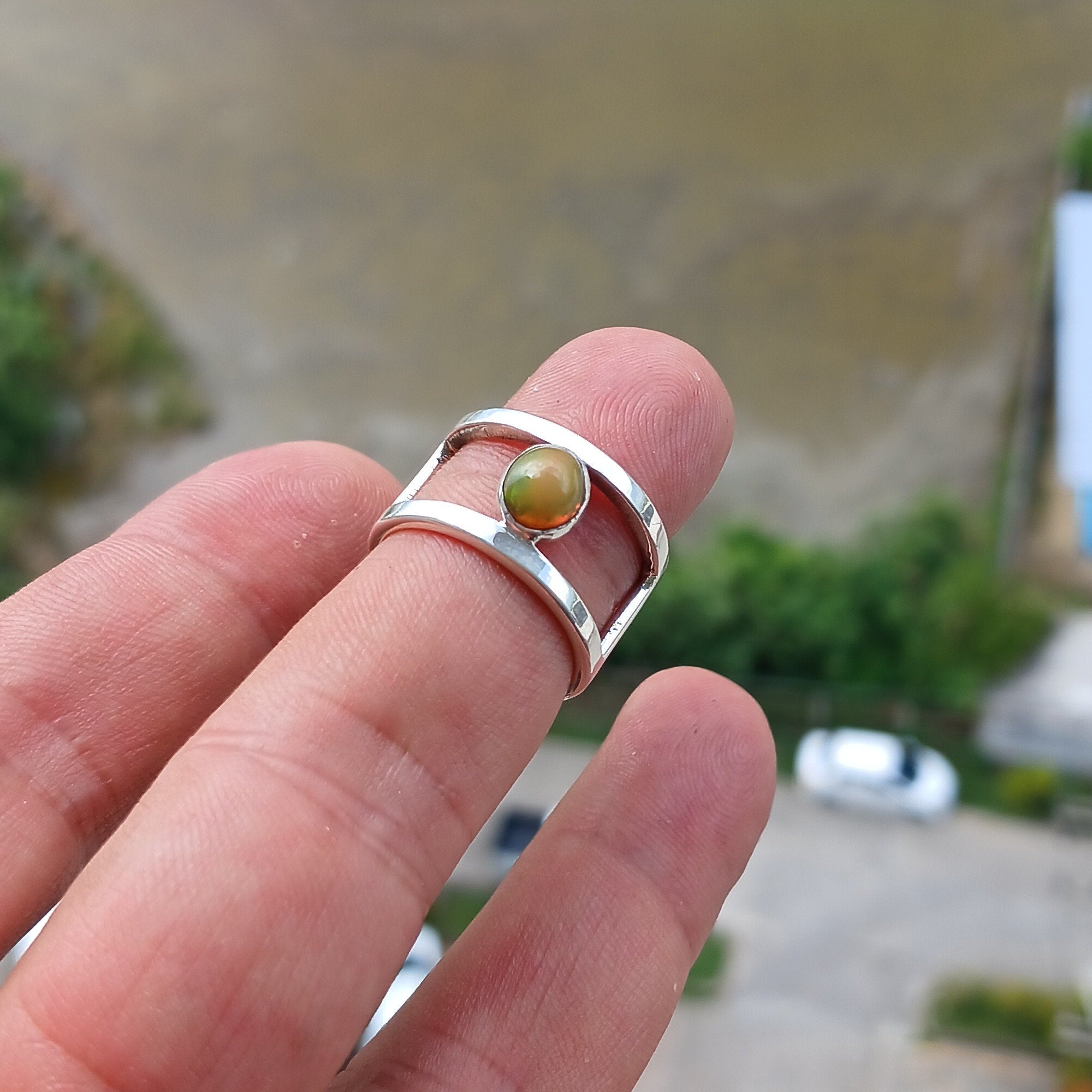 A handcrafted sterling silver solitaire ring featuring a vibrant oval opal, showcasing its unique colors and patterns.