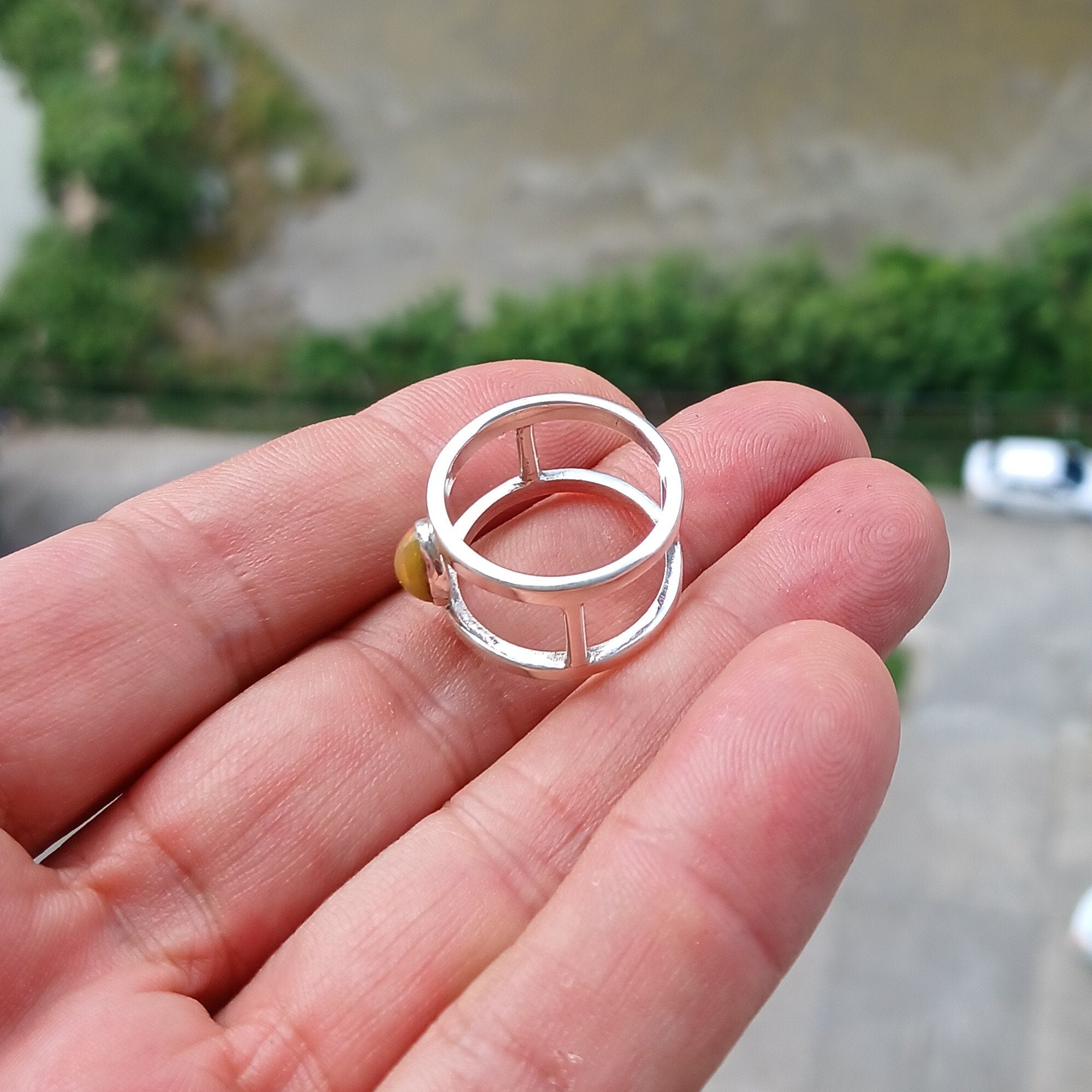 A handcrafted sterling silver solitaire ring featuring a vibrant oval opal, showcasing its unique colors and patterns.