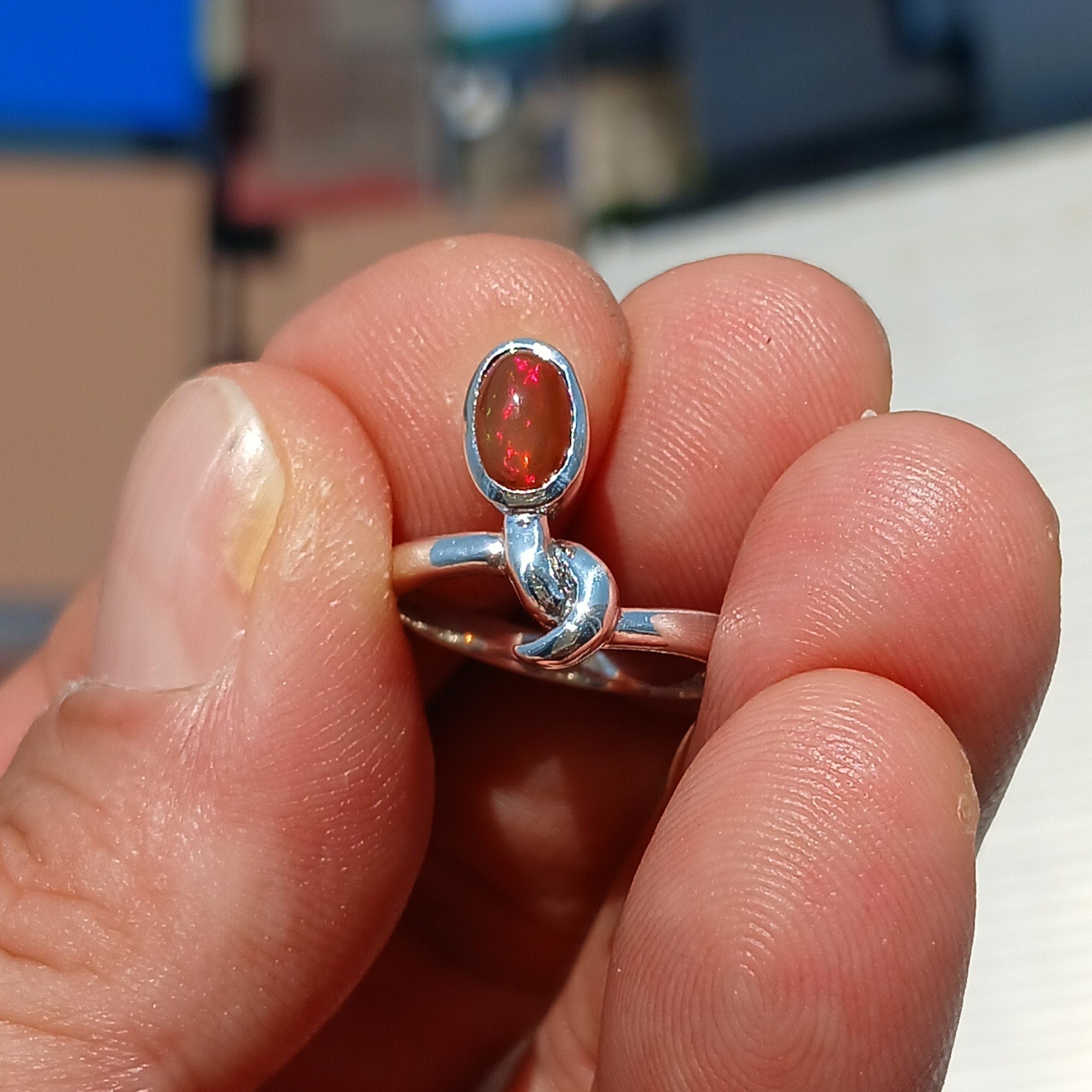 A stunning red opal ring set in polished sterling silver, featuring an oval-shaped opal that showcases vibrant colors and unique patterns.