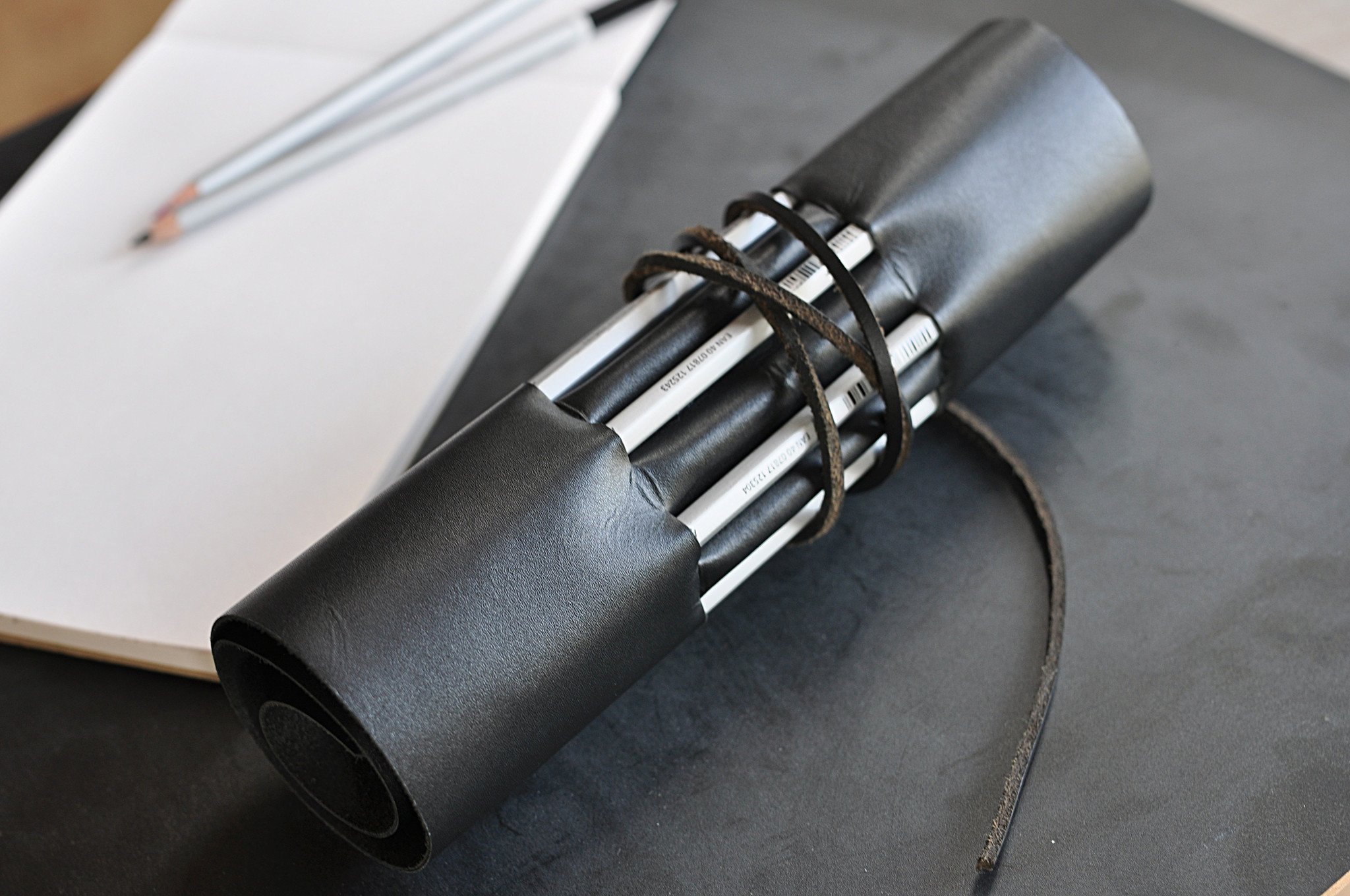 A stylish Pencil Wrap made from full grain cowhide leather, featuring 10 slots for pencils and pens, secured with a leather string closure.