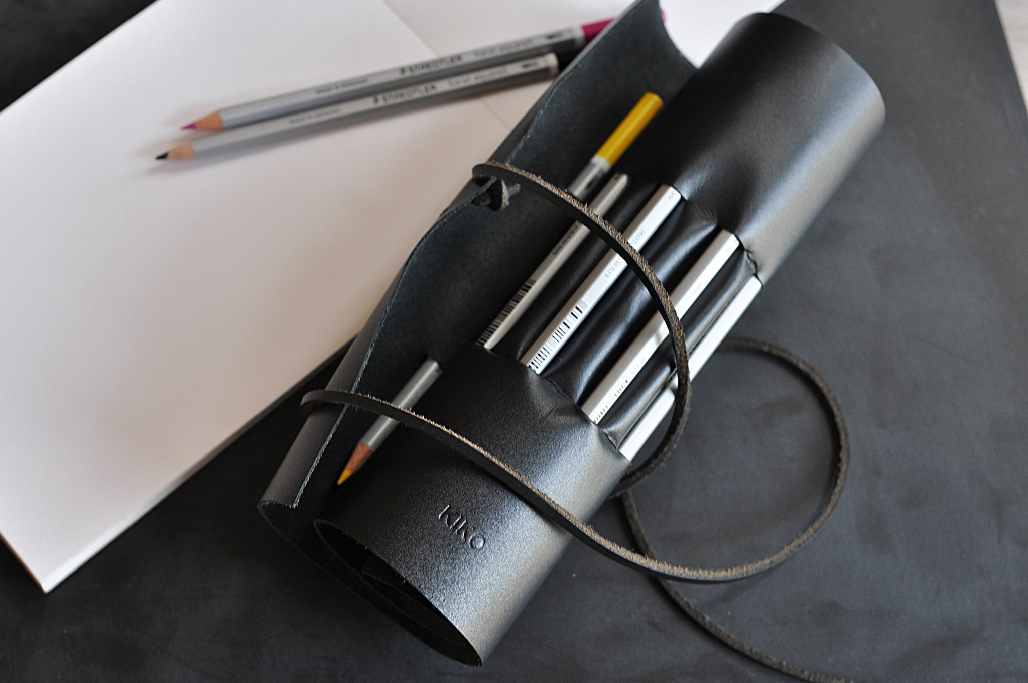 A stylish Pencil Wrap made from full grain cowhide leather, featuring 10 slots for pencils and pens, secured with a leather string closure.