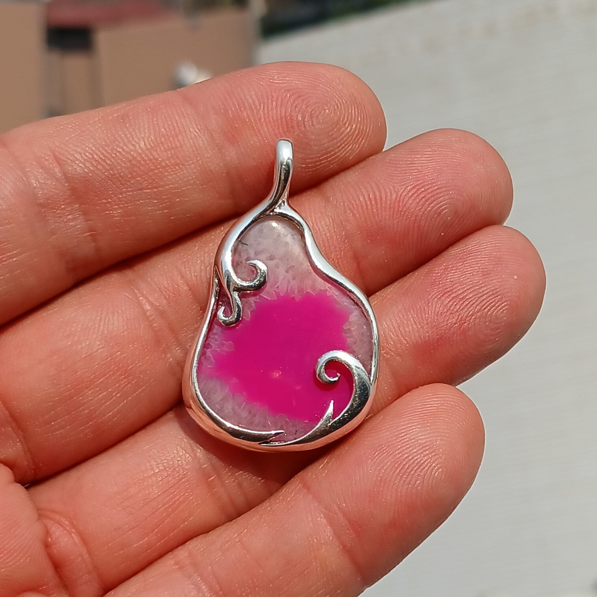 A stunning pink agate pendant in a pear shape, set in high-quality sterling silver, showcasing intricate artwork and natural beauty.