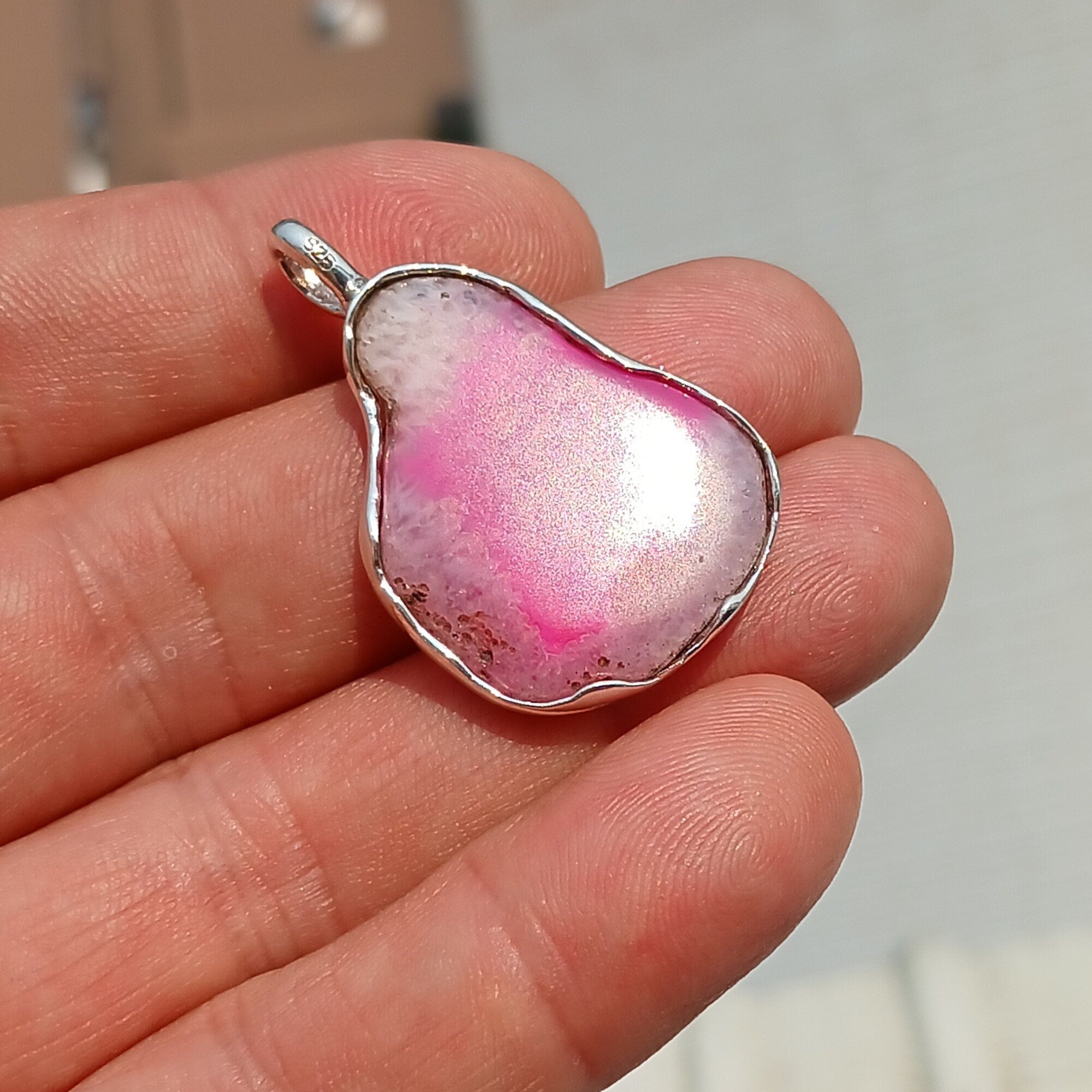 A stunning pink agate pendant in a pear shape, set in high-quality sterling silver, showcasing intricate artwork and natural beauty.