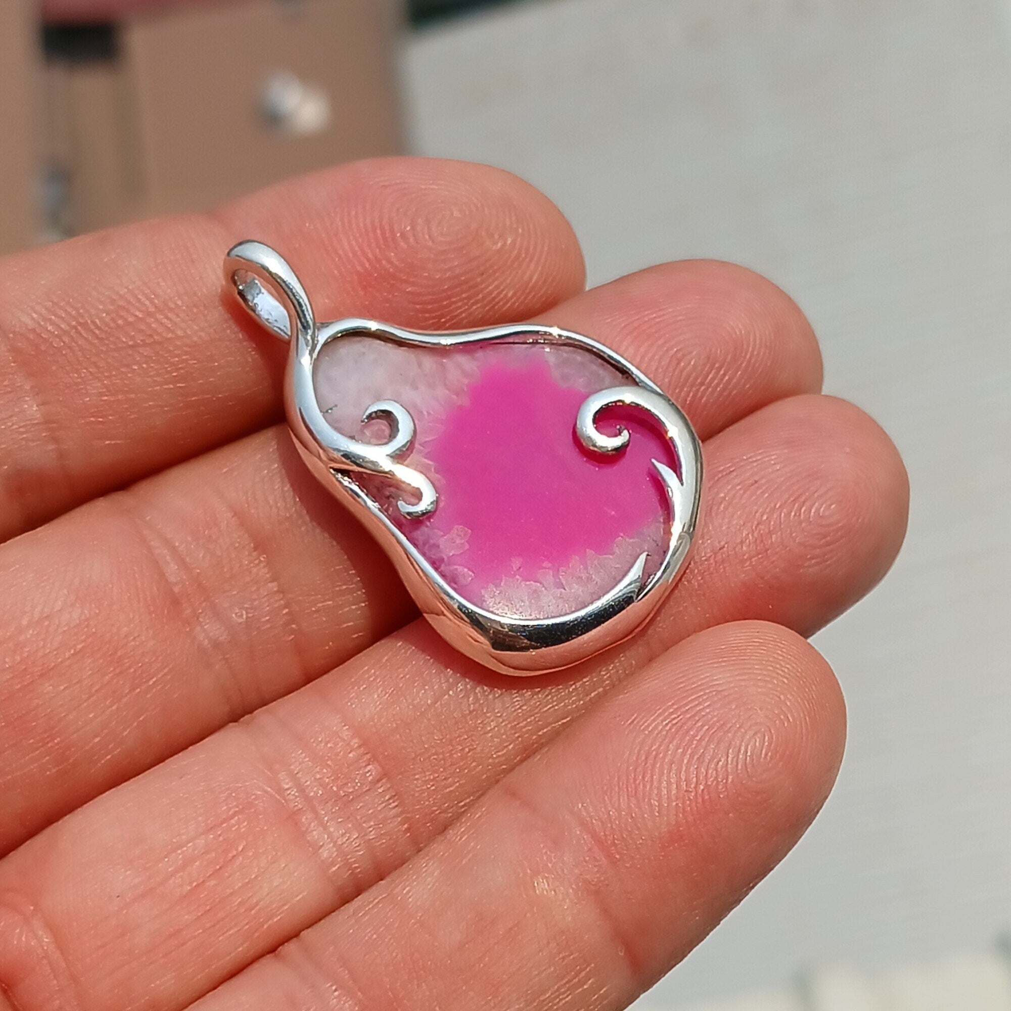 A stunning pink agate pendant in a pear shape, set in high-quality sterling silver, showcasing intricate artwork and natural beauty.