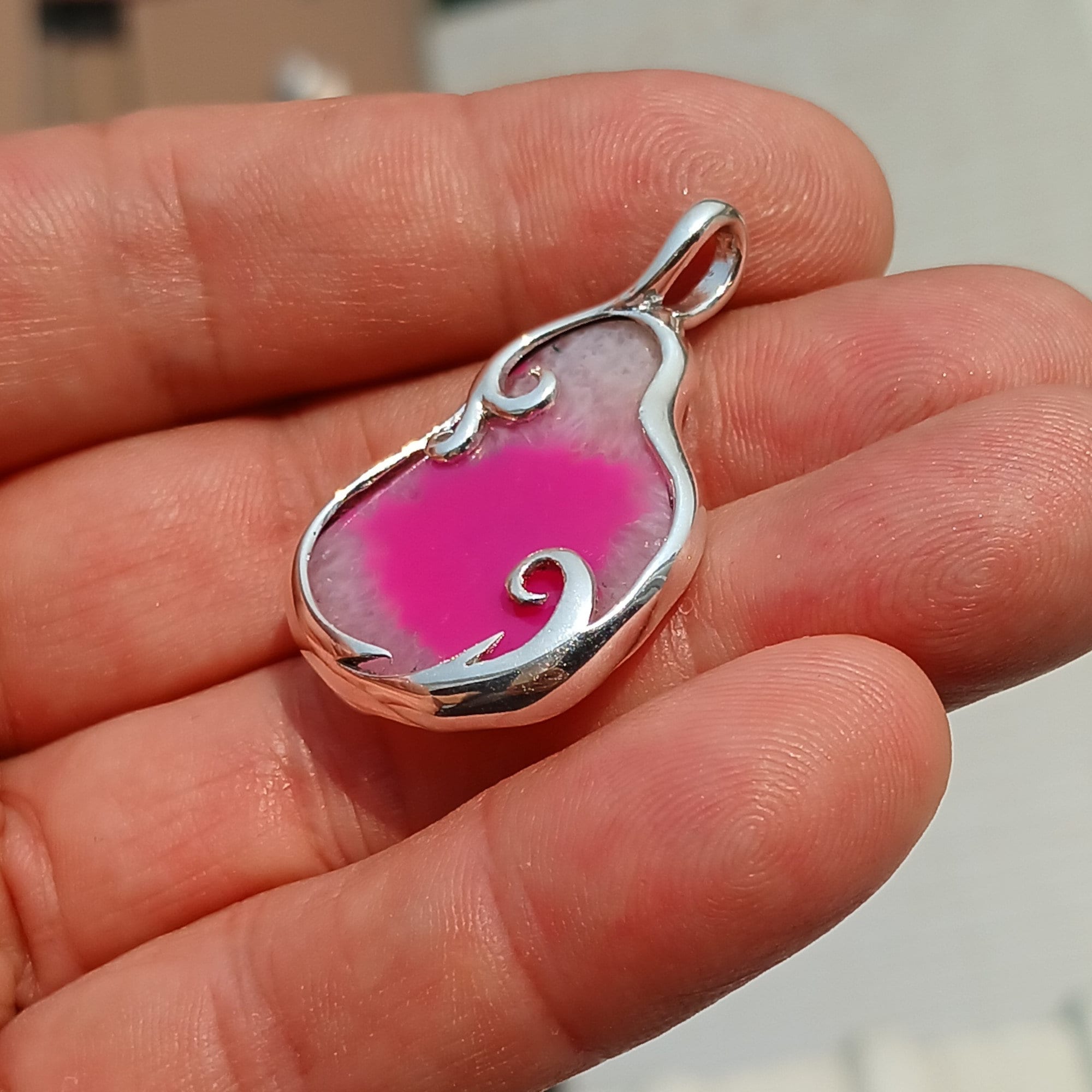 A stunning pink agate pendant in a pear shape, set in high-quality sterling silver, showcasing intricate artwork and natural beauty.