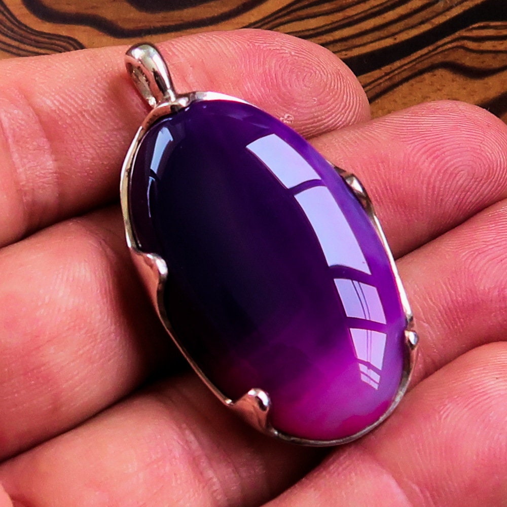 A beautiful Purple Agate Pendant set in sterling silver, showcasing a vibrant purple cabochon with intricate patterns.