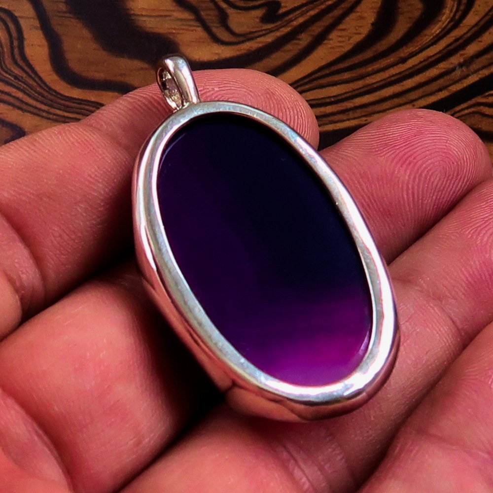 A beautiful Purple Agate Pendant set in sterling silver, showcasing a vibrant purple cabochon with intricate patterns.