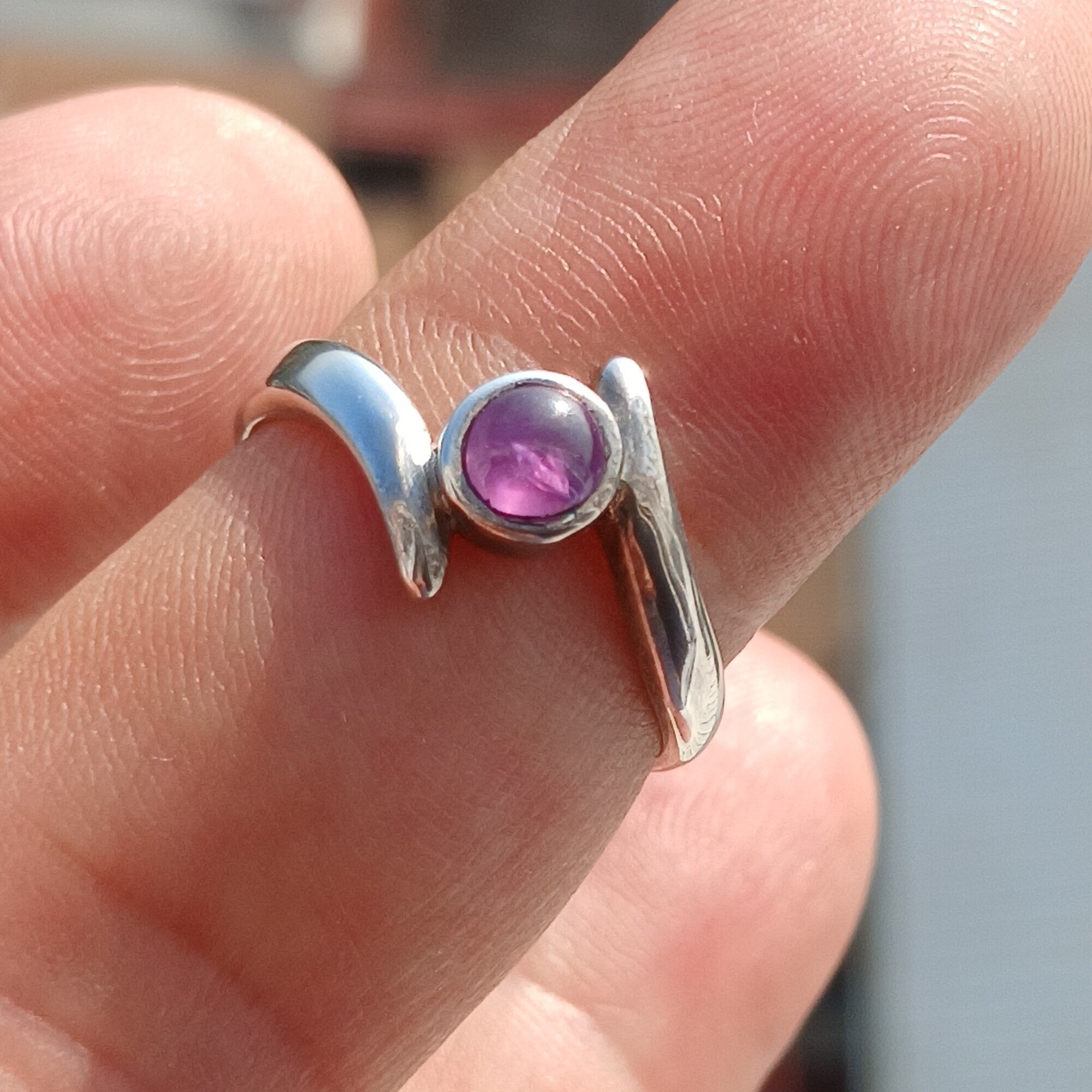 A beautiful purple star sapphire ring set in polished sterling silver, showcasing a unique star effect.