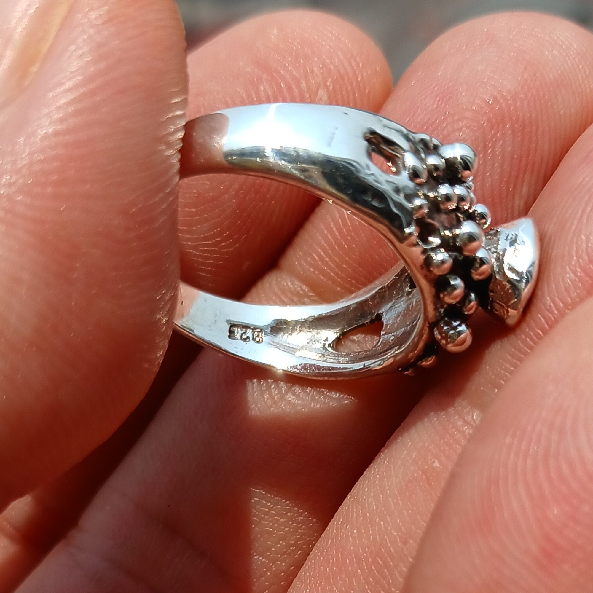 Artistic sterling silver ring featuring an oval cut red garnet, showcasing its deep red color and unique design.