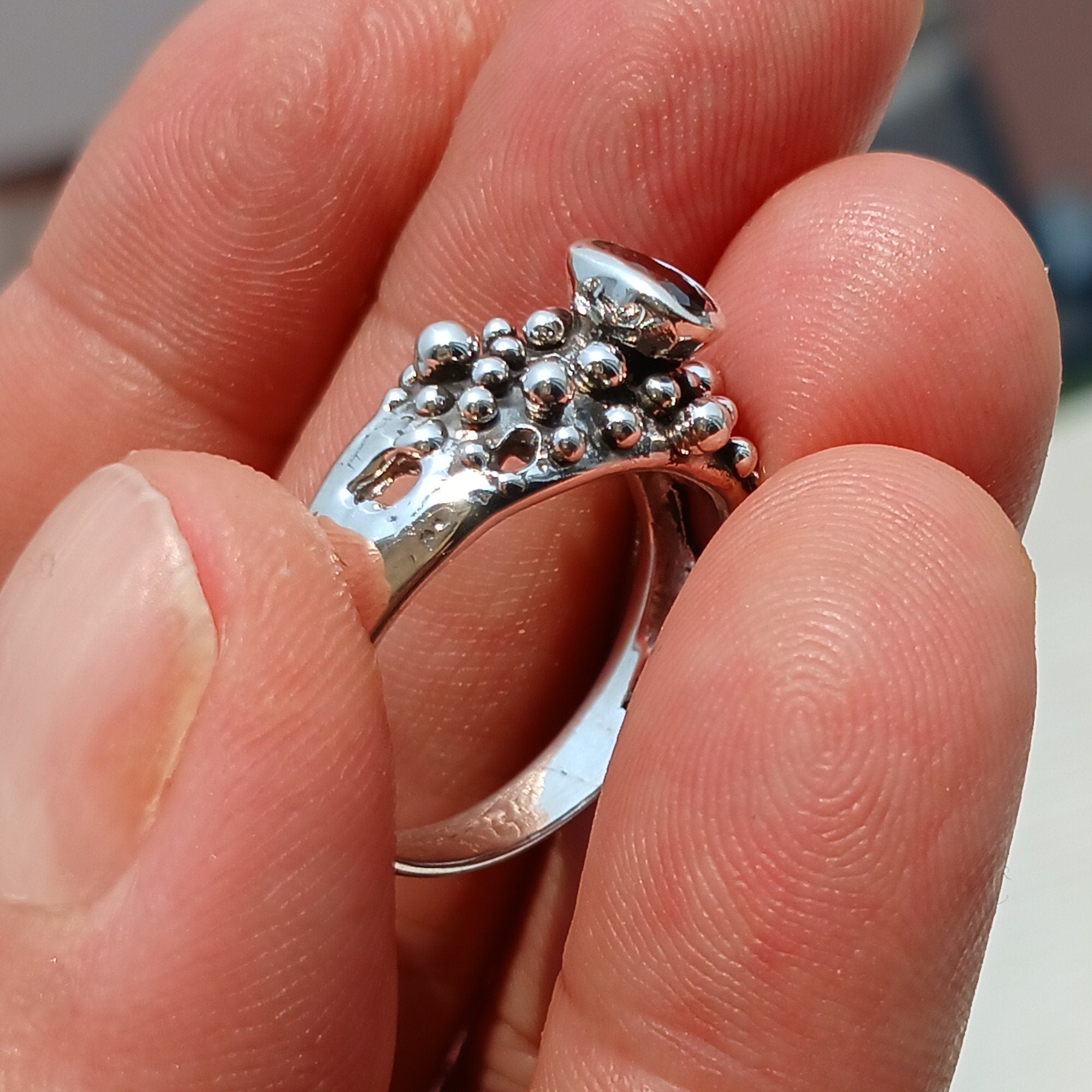 Artistic sterling silver ring featuring an oval cut red garnet, showcasing its deep red color and unique design.