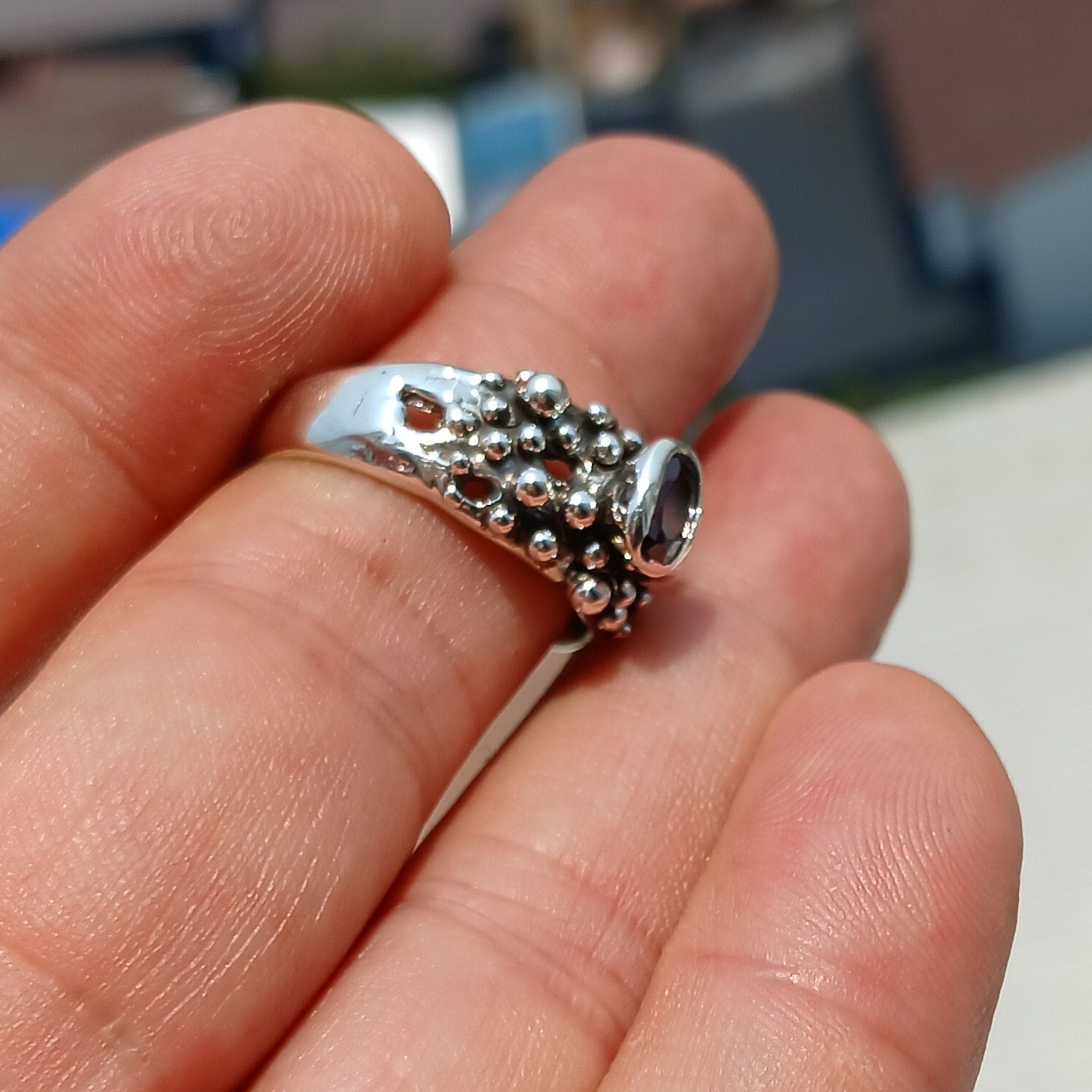 Artistic sterling silver ring featuring an oval cut red garnet, showcasing its deep red color and unique design.
