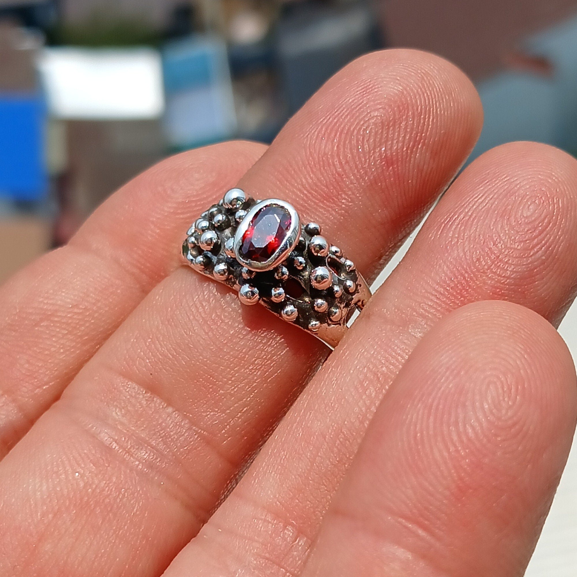 Artistic sterling silver ring featuring an oval cut red garnet, showcasing its deep red color and unique design.