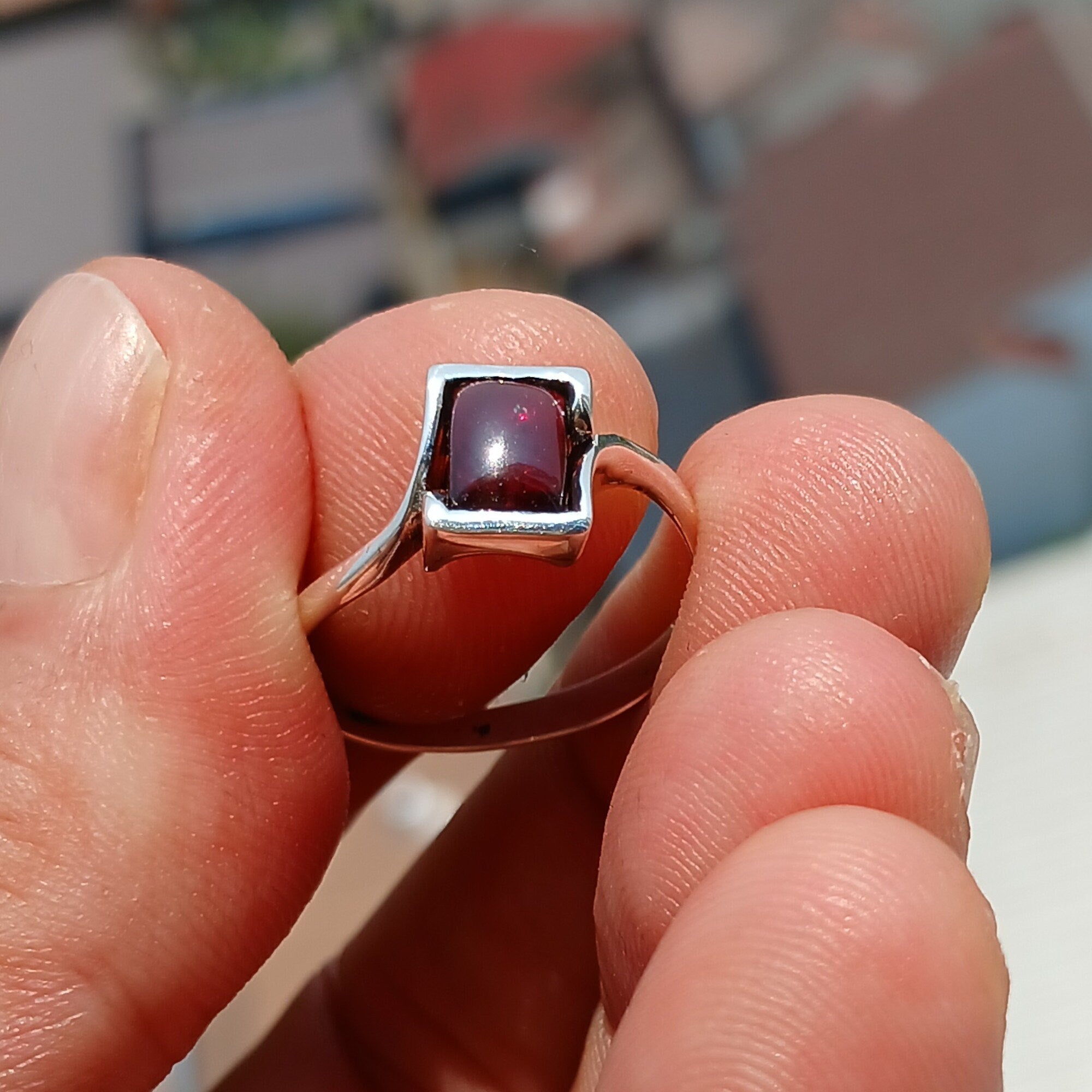 A beautiful Red Garnet Ring featuring a rectangle-shaped cabochon set in a polished sterling silver band, showcasing its vibrant red color.