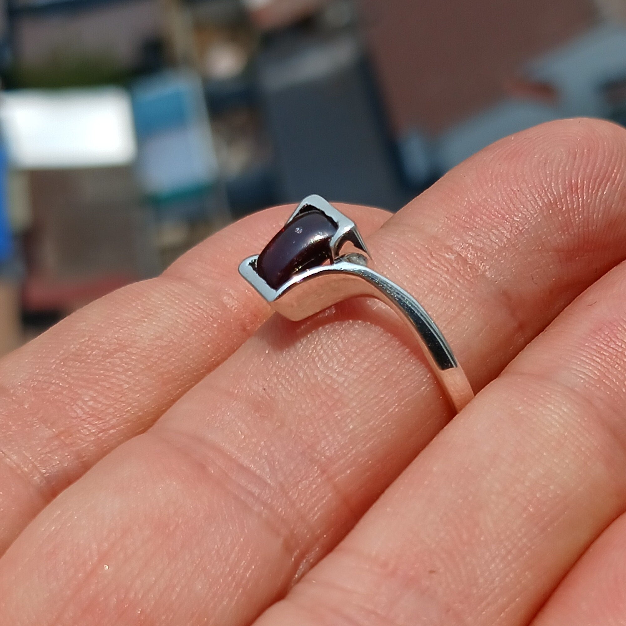 A beautiful Red Garnet Ring featuring a rectangle-shaped cabochon set in a polished sterling silver band, showcasing its vibrant red color.