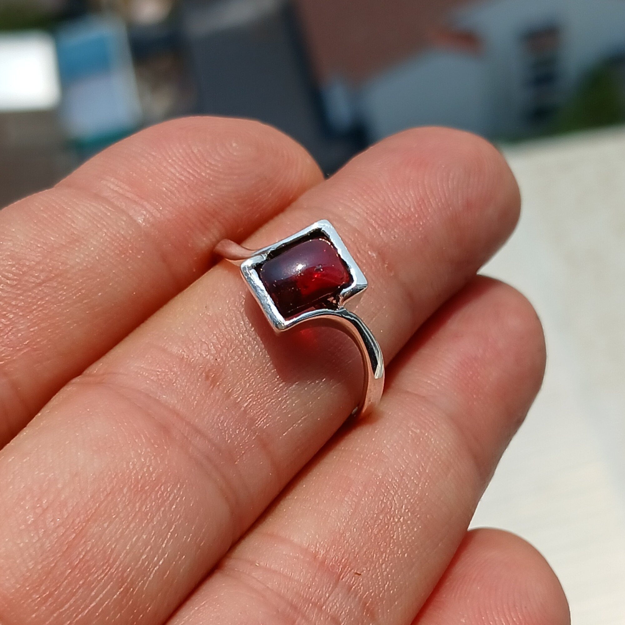 A beautiful Red Garnet Ring featuring a rectangle-shaped cabochon set in a polished sterling silver band, showcasing its vibrant red color.