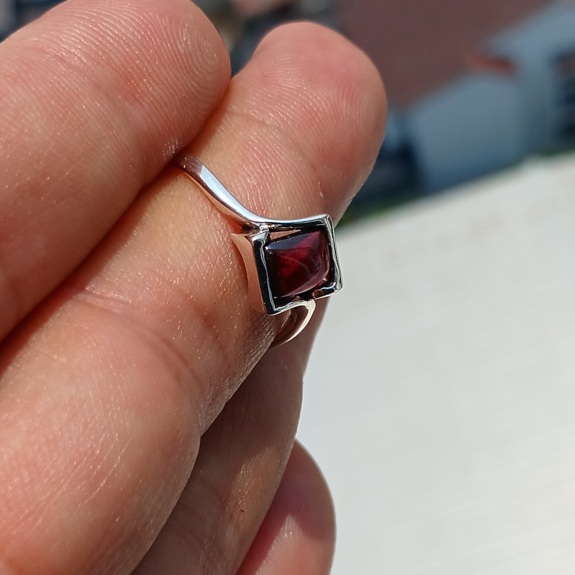 A beautiful Red Garnet Ring featuring a rectangle-shaped cabochon set in a polished sterling silver band, showcasing its vibrant red color.