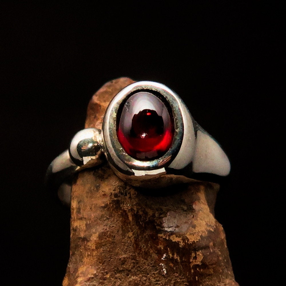 A stunning Red Garnet Ring featuring an oval-shaped red Garnet cabochon set in polished Sterling Silver, showcasing its elegant design.