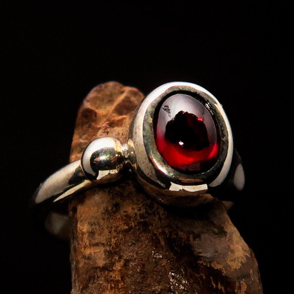 A stunning Red Garnet Ring featuring an oval-shaped red Garnet cabochon set in polished Sterling Silver, showcasing its elegant design.