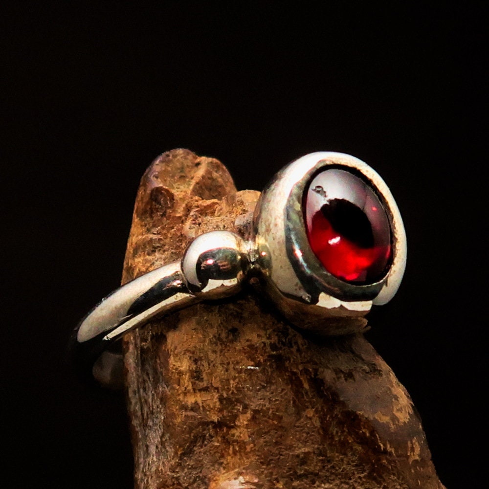 A stunning Red Garnet Ring featuring an oval-shaped red Garnet cabochon set in polished Sterling Silver, showcasing its elegant design.