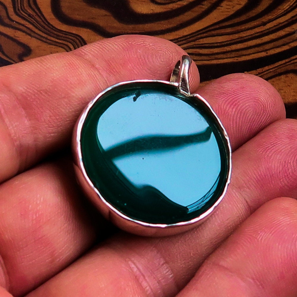 Round Agate Pendant in sterling silver featuring a green Agate cabochon, showcasing intricate design and elegant bail.