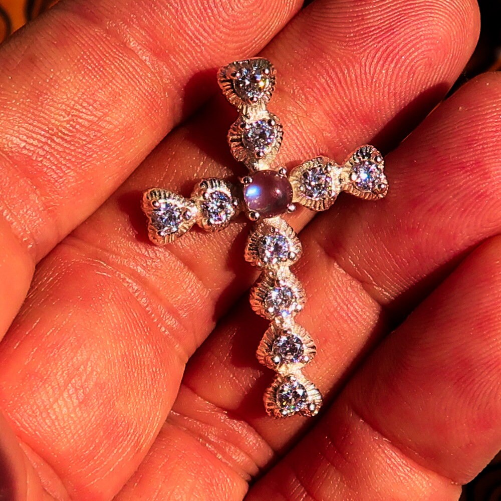 A stunning silver crucifix pendant featuring a moonstone and cubic zirconia, elegantly crafted in sterling silver.