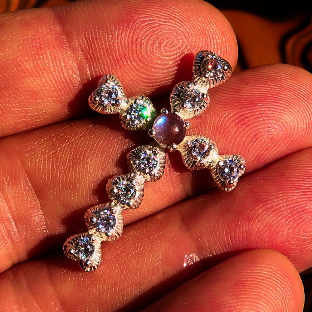 A stunning silver crucifix pendant featuring a moonstone and cubic zirconia, elegantly crafted in sterling silver.