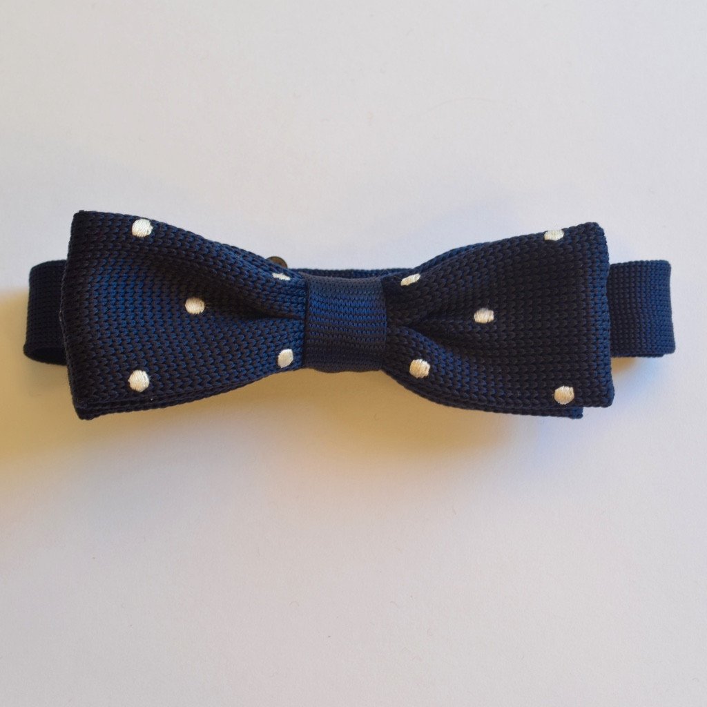 Slim navy blue and white polka dot knitted bow tie, elegantly crafted with a playful design, perfect for formal and casual occasions.