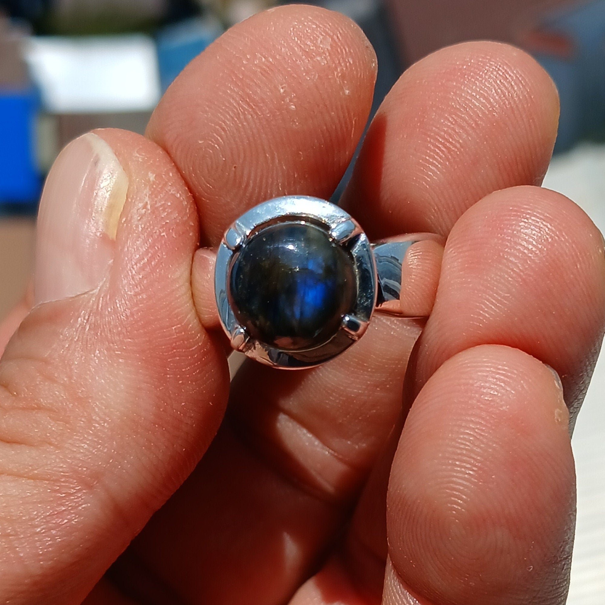 A handcrafted sterling silver ring featuring a round dark Labradorite stone, showcasing its unique design and craftsmanship.