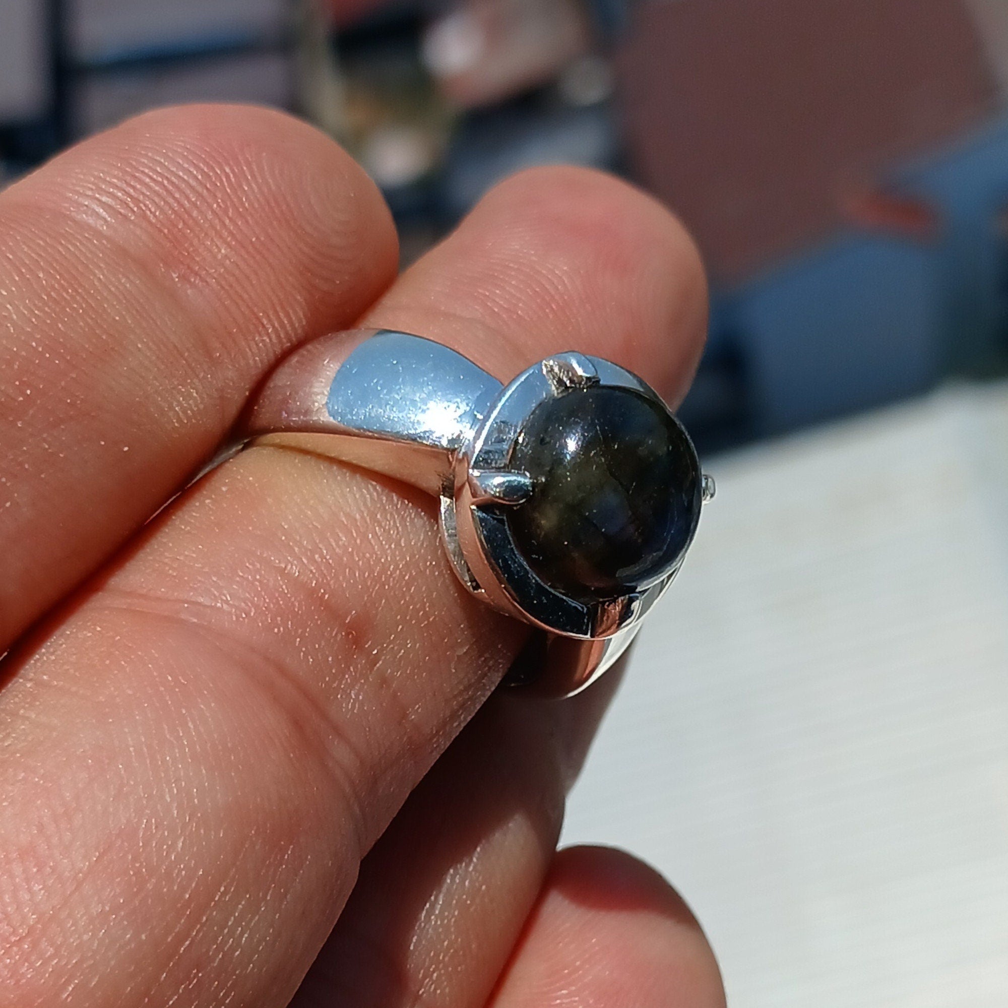 A handcrafted sterling silver ring featuring a round dark Labradorite stone, showcasing its unique design and craftsmanship.